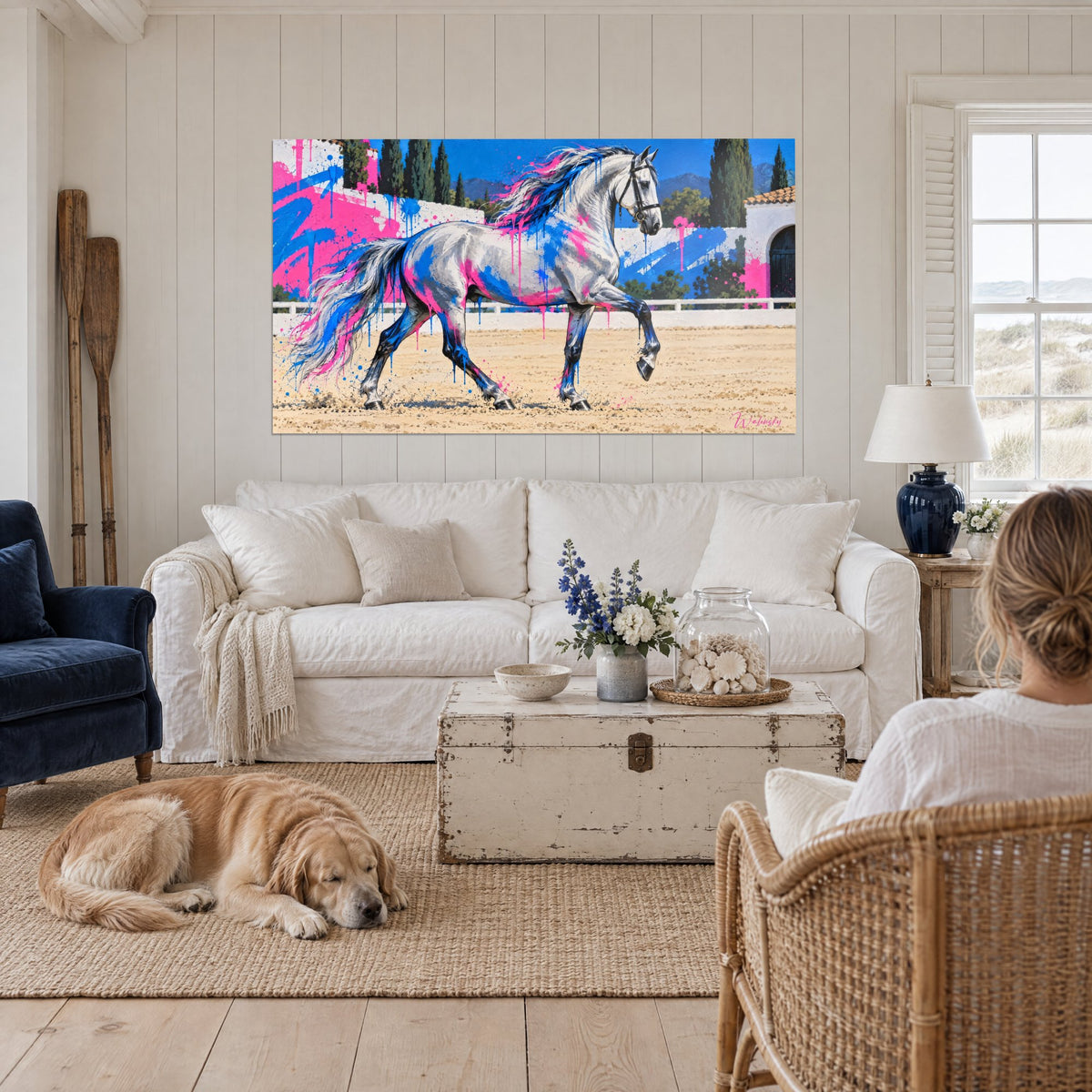 Tableau étalon gris pommelé au trot, éclaboussures roses et bleues sur le pelage, au-dessus d'un canapé dans un salon lumineux