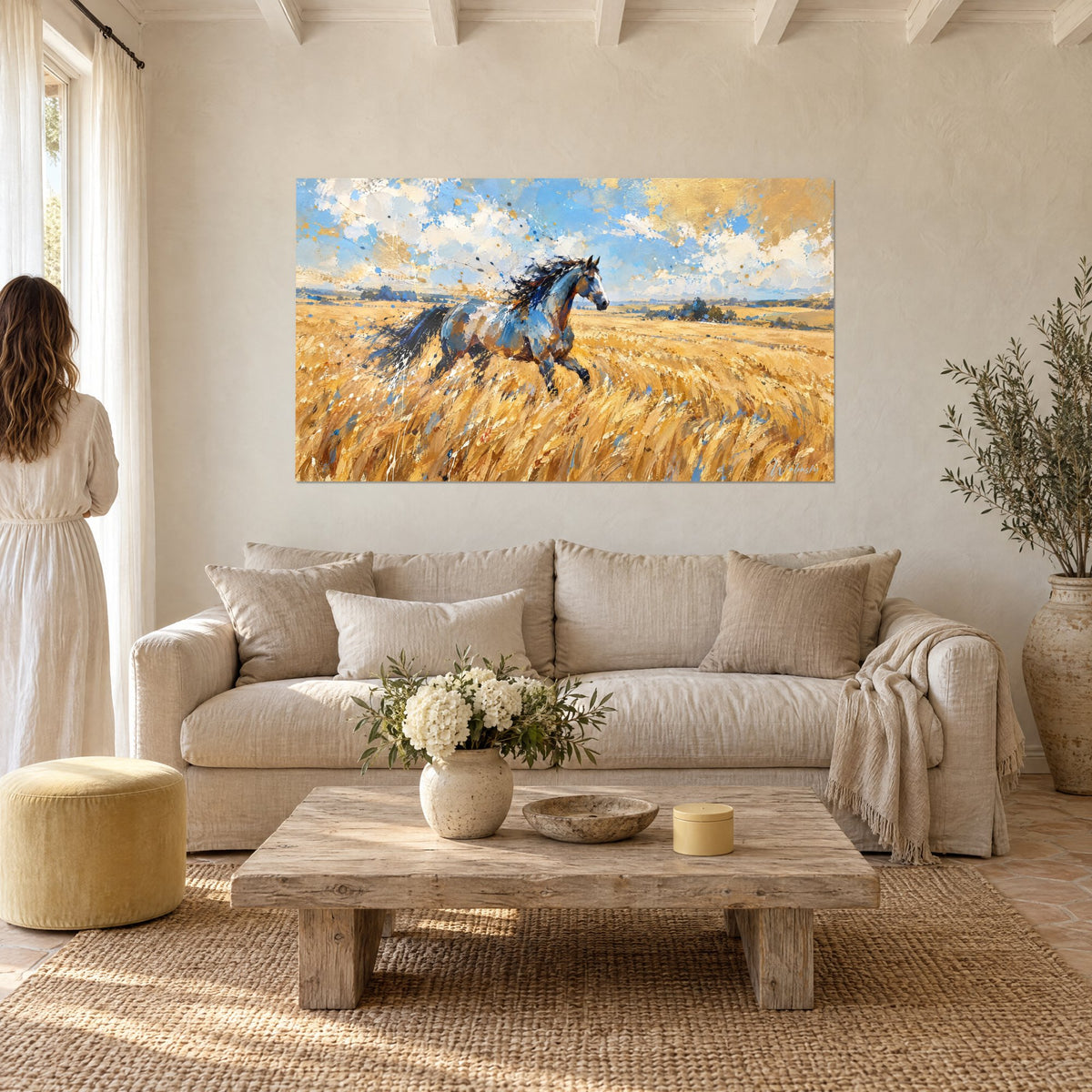 Tableau cheval gris-bleu au galop dans un blé doré, ciel moucheté d'or, deux personnes de dos au-dessus d'un canapé dans un salon lumineux