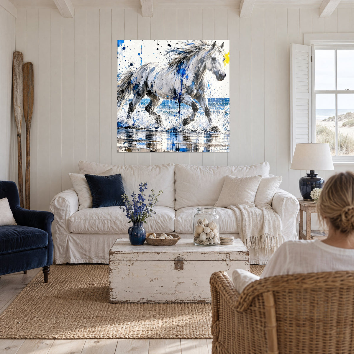 Tableau cheval blanc galopant dans l'écume, taches bleu cobalt et jaune, au-dessus d'un canapé dans un salon lumineux