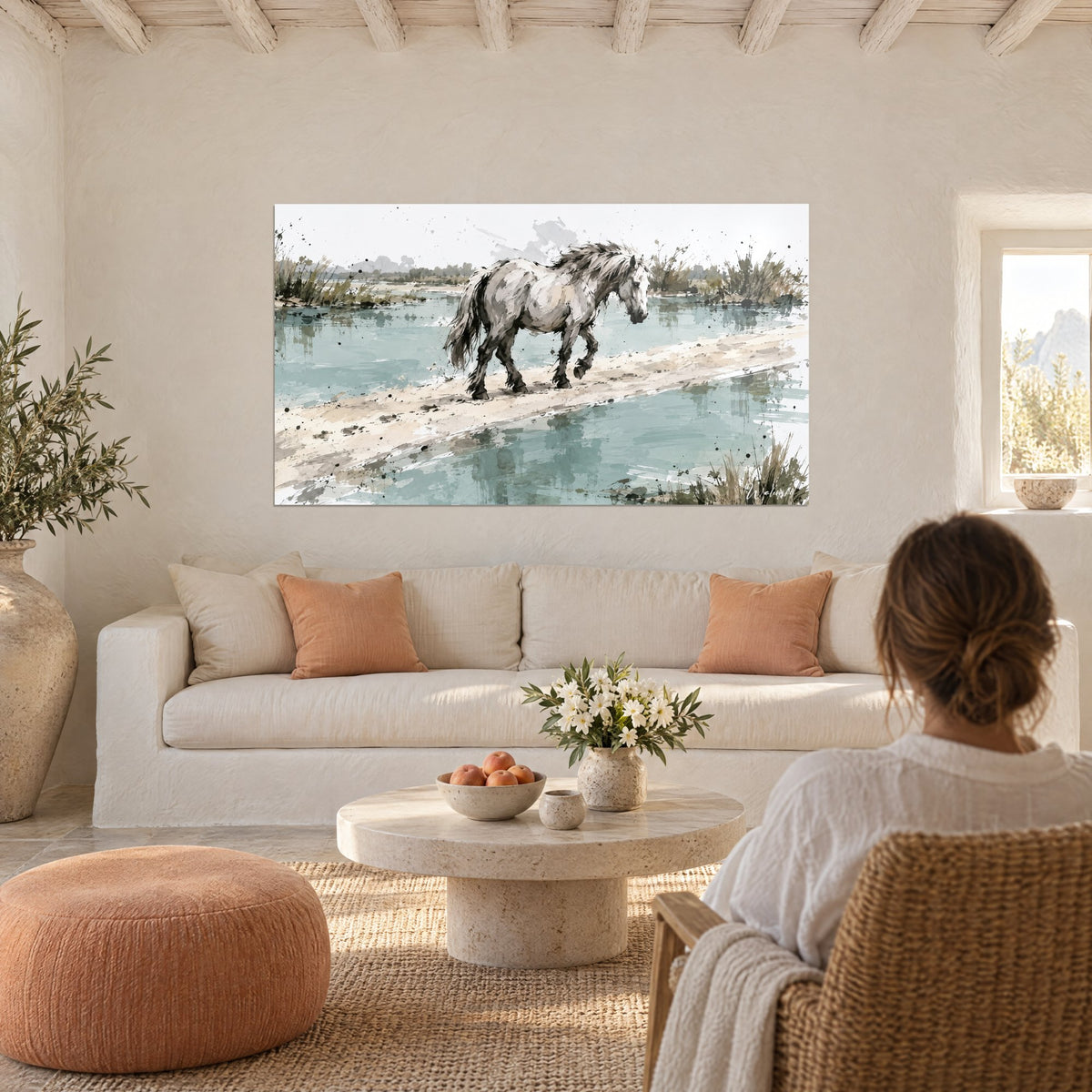 Tableau cheval camarguais gris pommelé avançant sur un banc de sable beige entre eaux turquoise, au-dessus d'un canapé dans un salon lumineux