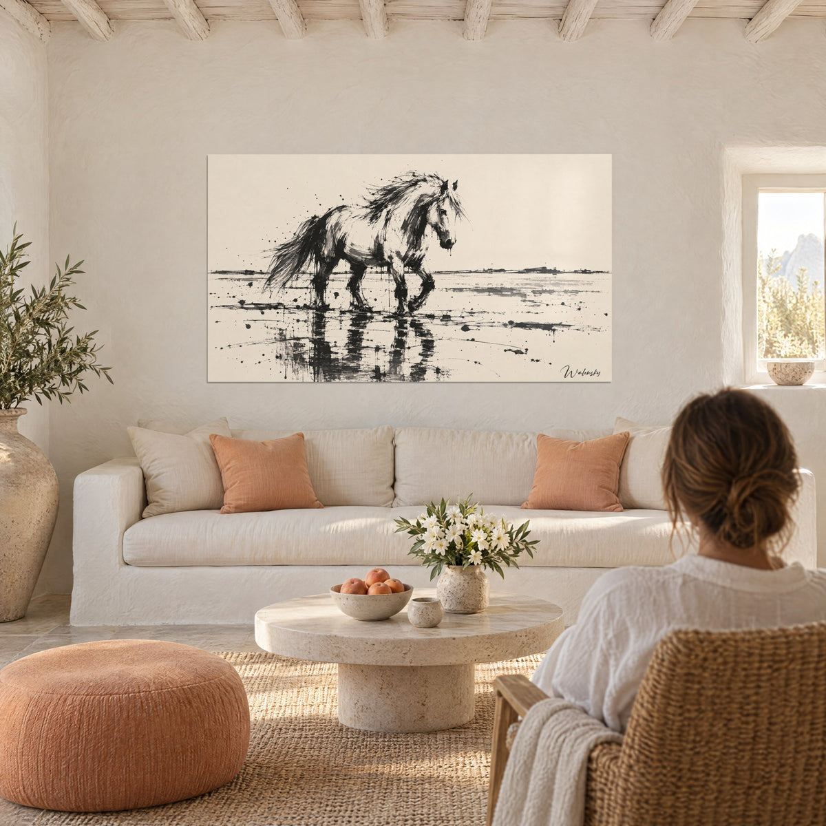 Tableau étalon d'encre noire foulant l'eau, crinière ébouriscée sur fond beige crème, au-dessus d'un canapé dans un salon lumineux