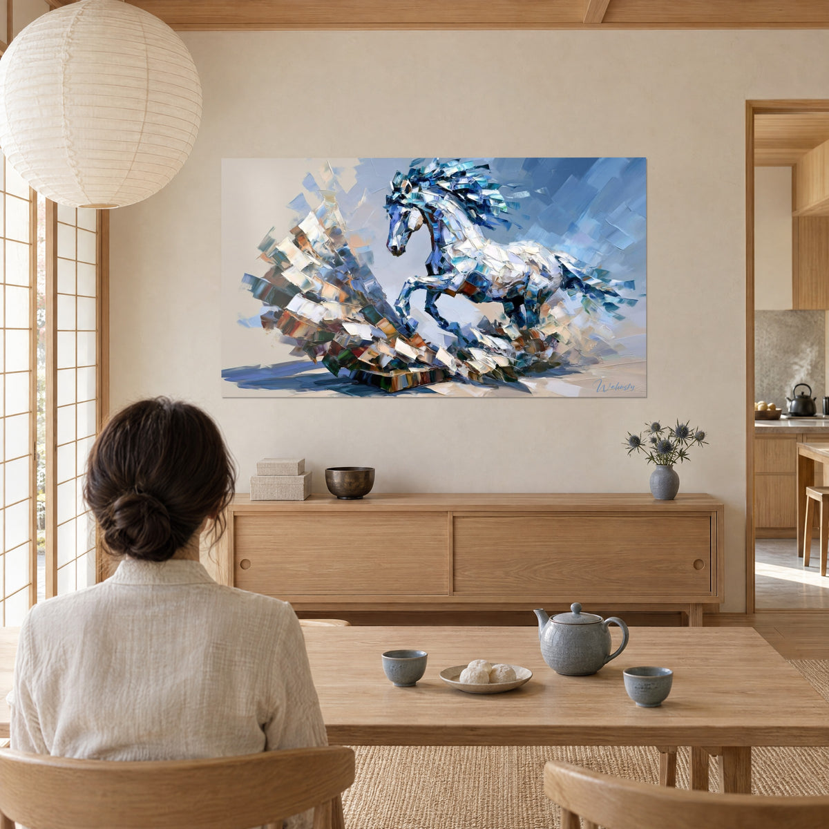Tableau pur-sang bondissant en coups de couteau bleu nuit et blanc perlé, femme de dos devant un buffet en bois clair