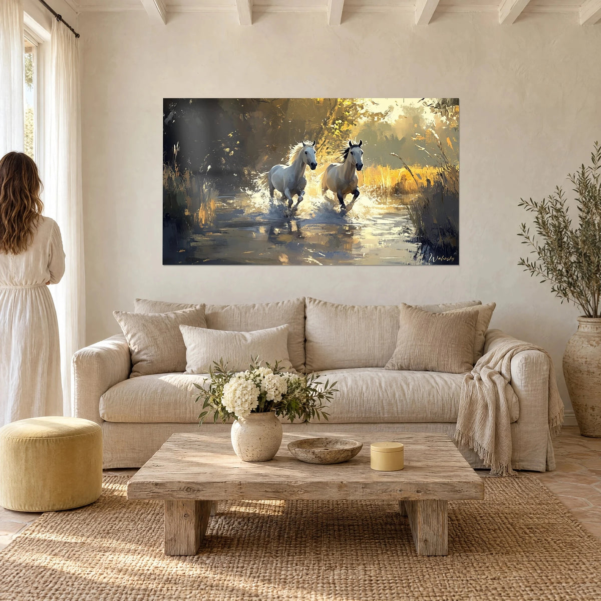 Wall art two white horses galloping through water, silver spray and golden foliage, above a sofa in a bright living room
