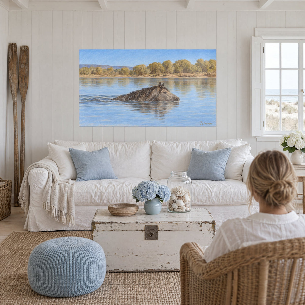 Tableau mustang gris nageant dans une eau bleue, saules dorés en rive, au-dessus d'un canapé dans un salon lumineux