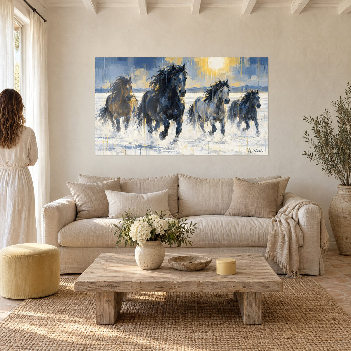 Tableau quatre chevaux noirs et ocre lancés dans l'eau, soleil jaune pâle, au-dessus d'un canapé dans un salon lumineux