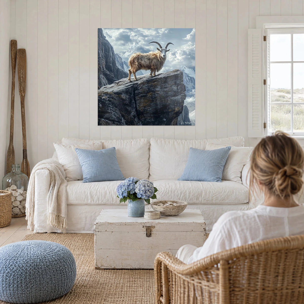 Gemälde Steinbock mit goldenem Fell auf einem grauen Felsen, blauer bewölkter Himmel, über einem Sofa in einem hellen Wohnzimmer