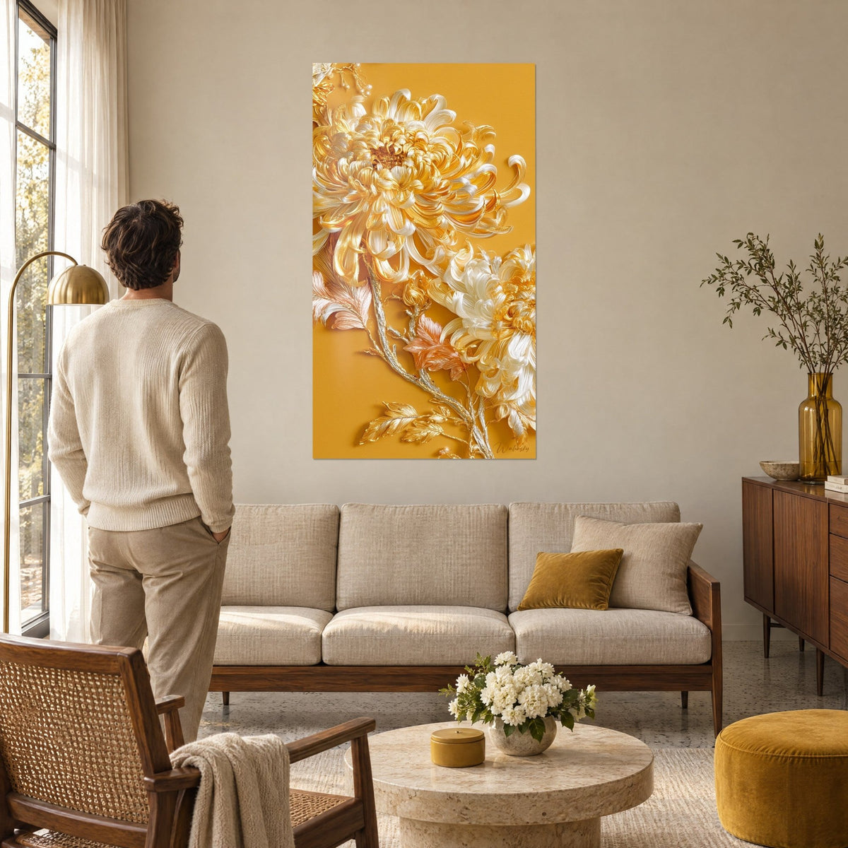 Tableau chrysanthèmes dorés aux pétales en relief sur fond jaune moutarde, homme de dos, au-dessus d'un canapé dans un salon lumineux