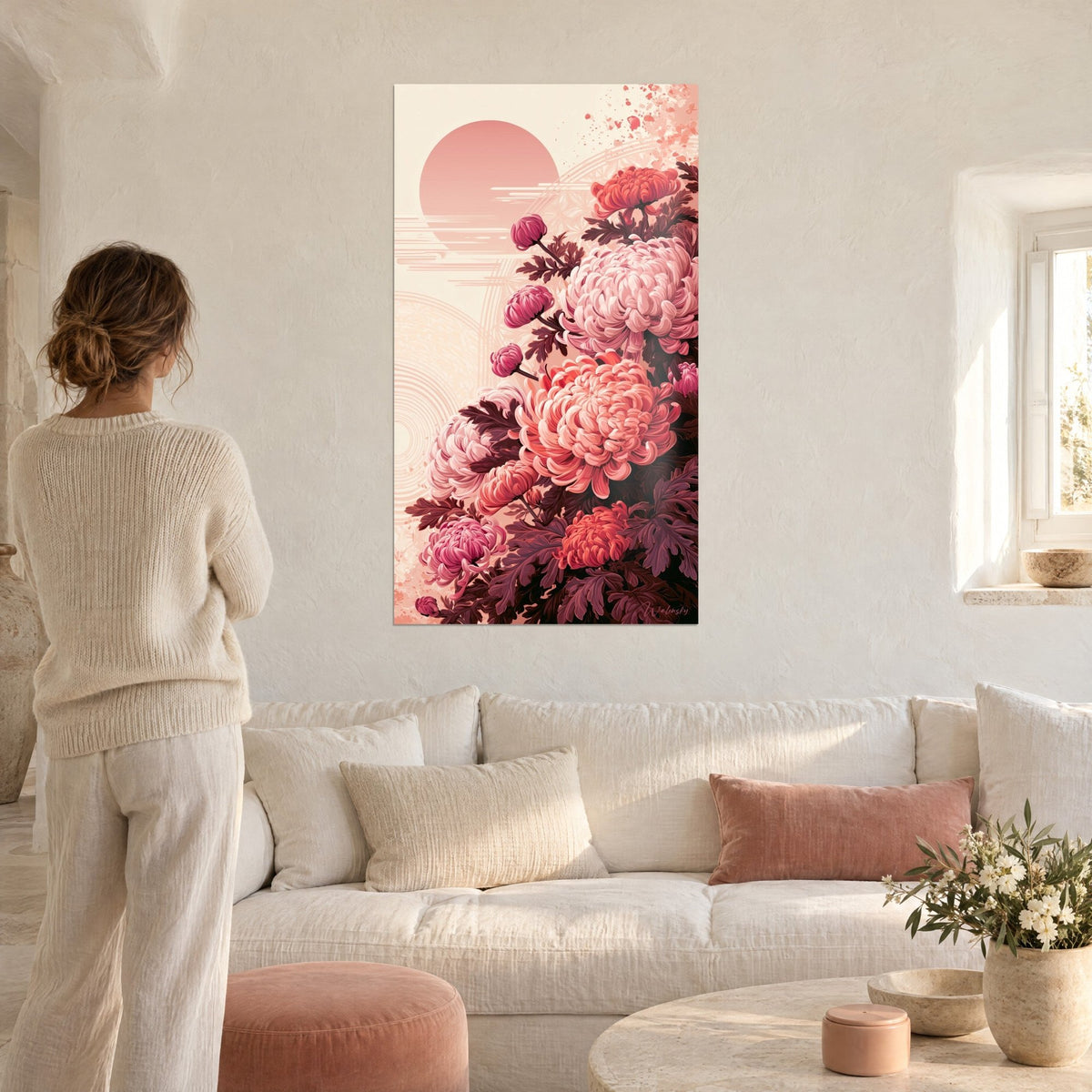 Tableau chrysanthèmes rose poudré et corail devant un soleil rond pâle, femme de dos, au-dessus d'un canapé dans un salon lumineux