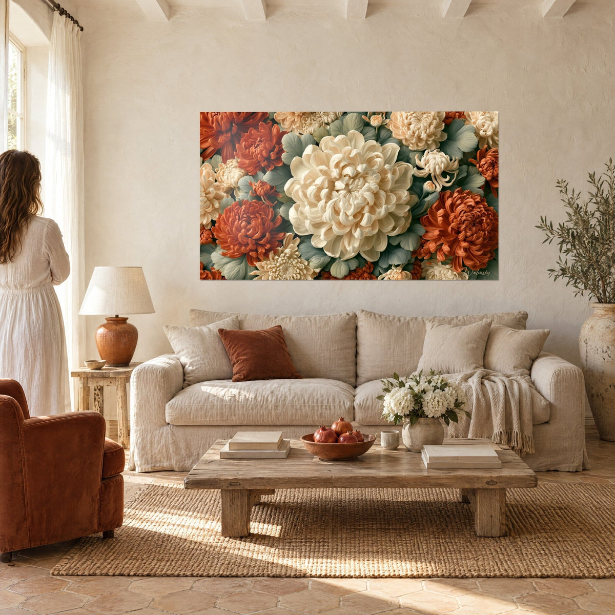 Tableau chrysanthème ivoire aux pétales frisés, entouré de roux et de feuilles vert sauge, au-dessus d'un canapé dans un salon lumineux