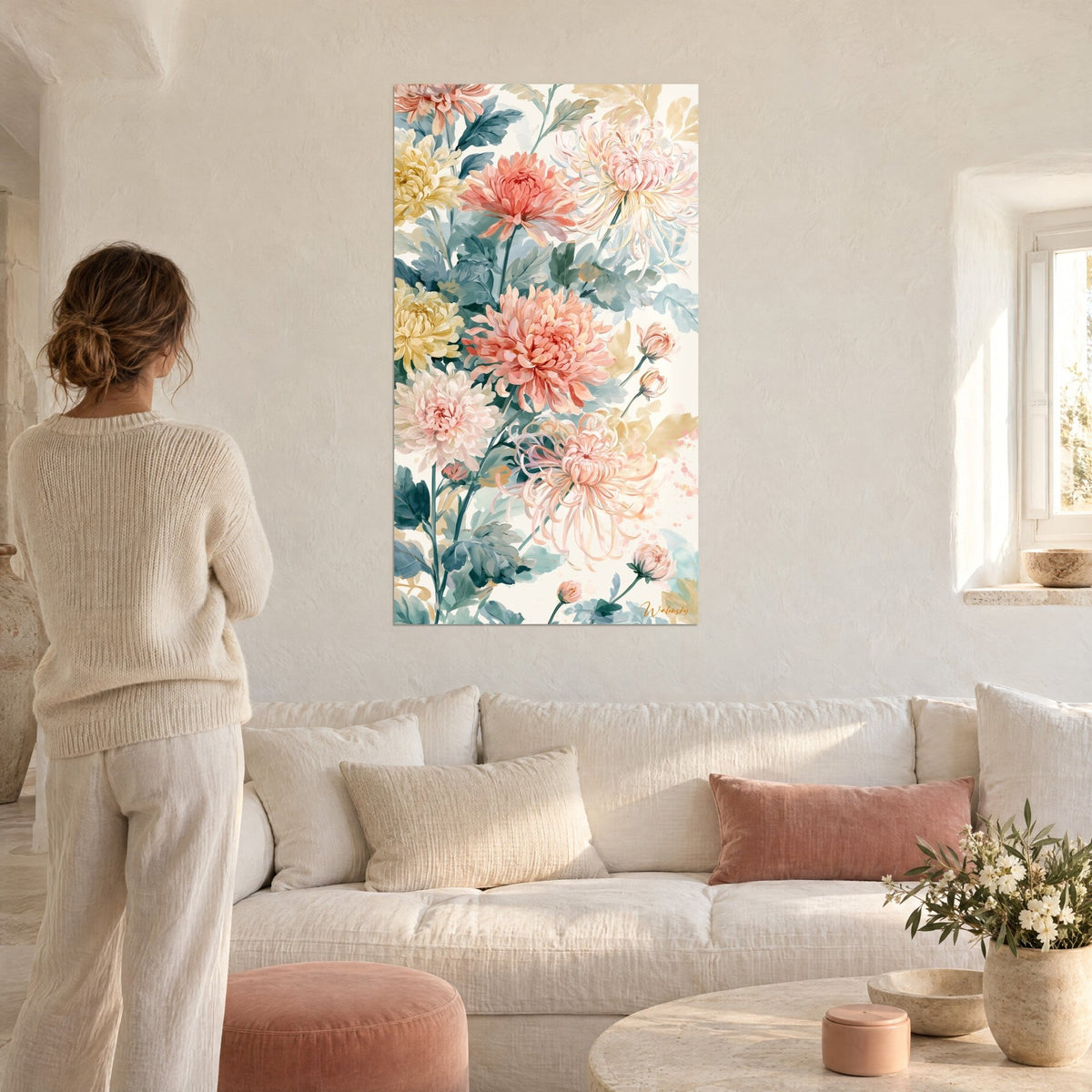 Tableau grands chrysanthèmes corail et jaune pâle en aquarelle, une femme de dos au-dessus d'un canapé dans un salon lumineux