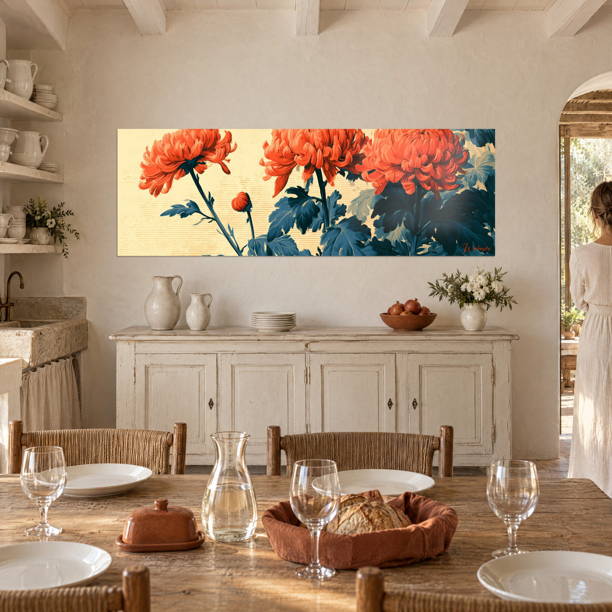 Cuadro de flores otoñales rojo anaranjadas de pétalos ondulados, fondo beige rayado, aparador blanco y mesa puesta de un mas