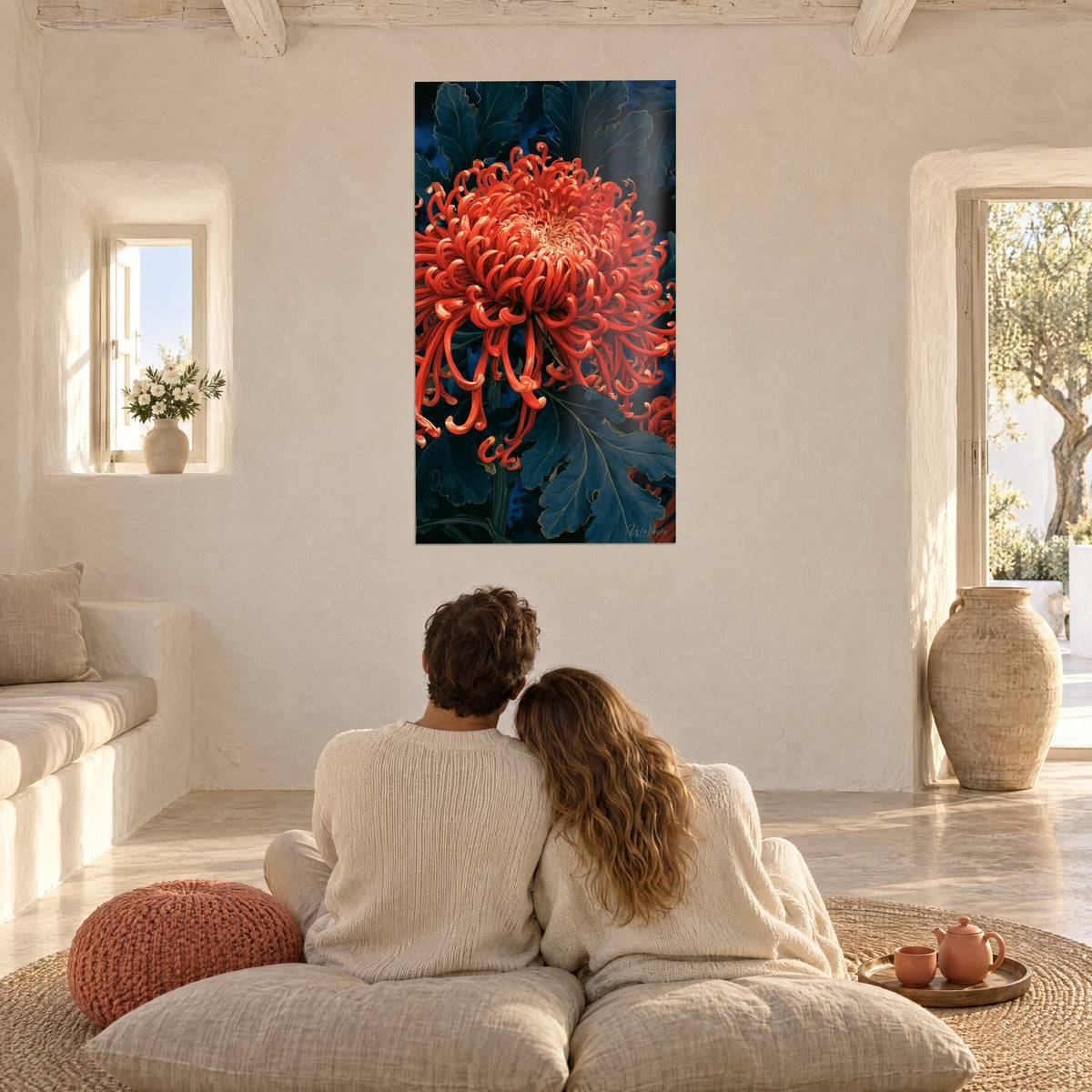 Cuadro flor bermellón con pétalos rizados sobre follaje azul noche, pareja abrazada sobre cojines beige, paredes blancas redondeadas