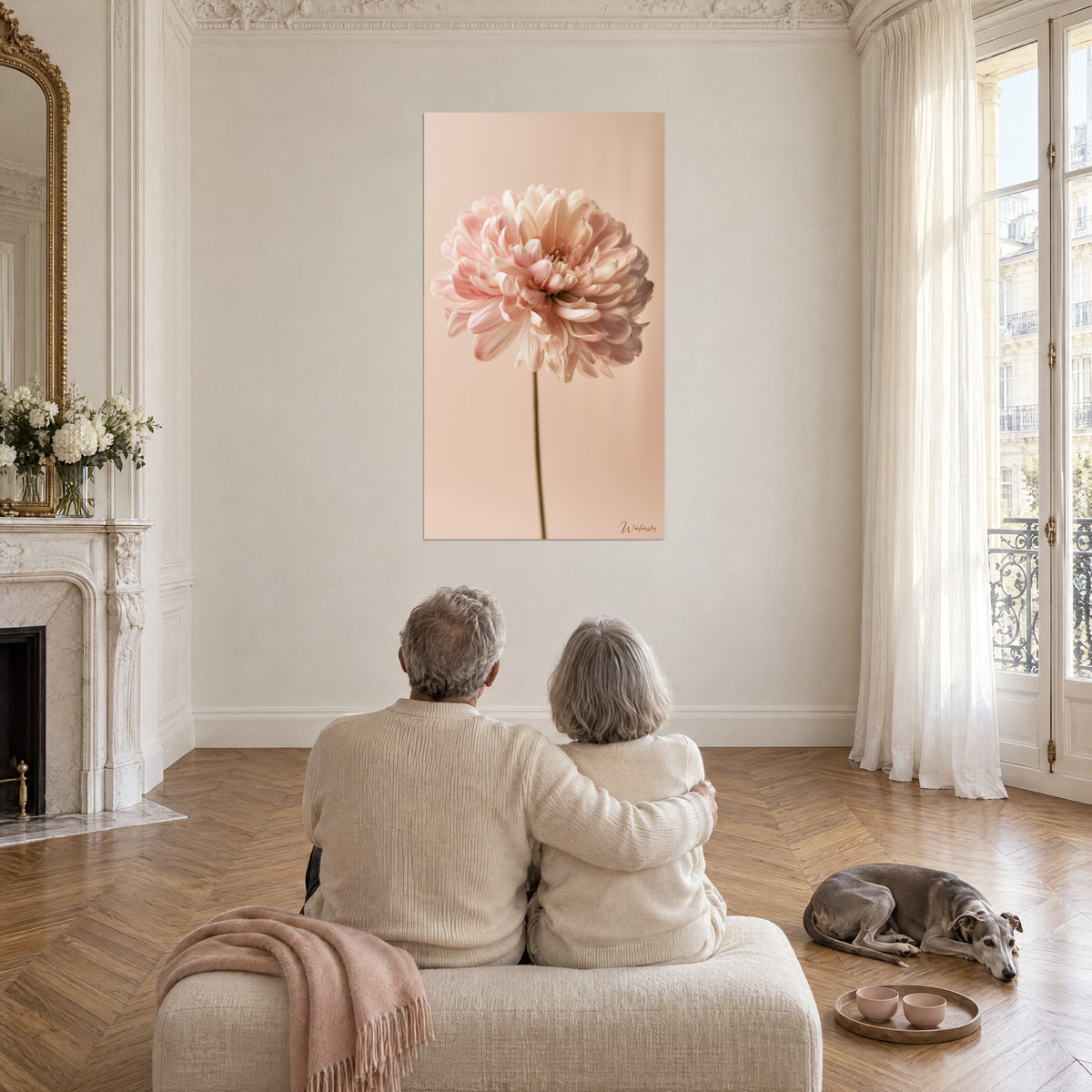 Quadro grande fiore rotondo rosa pallido e bianco cremoso su sfondo beige rosato, coppia di spalle su un divano, whippet sdraiato a terra