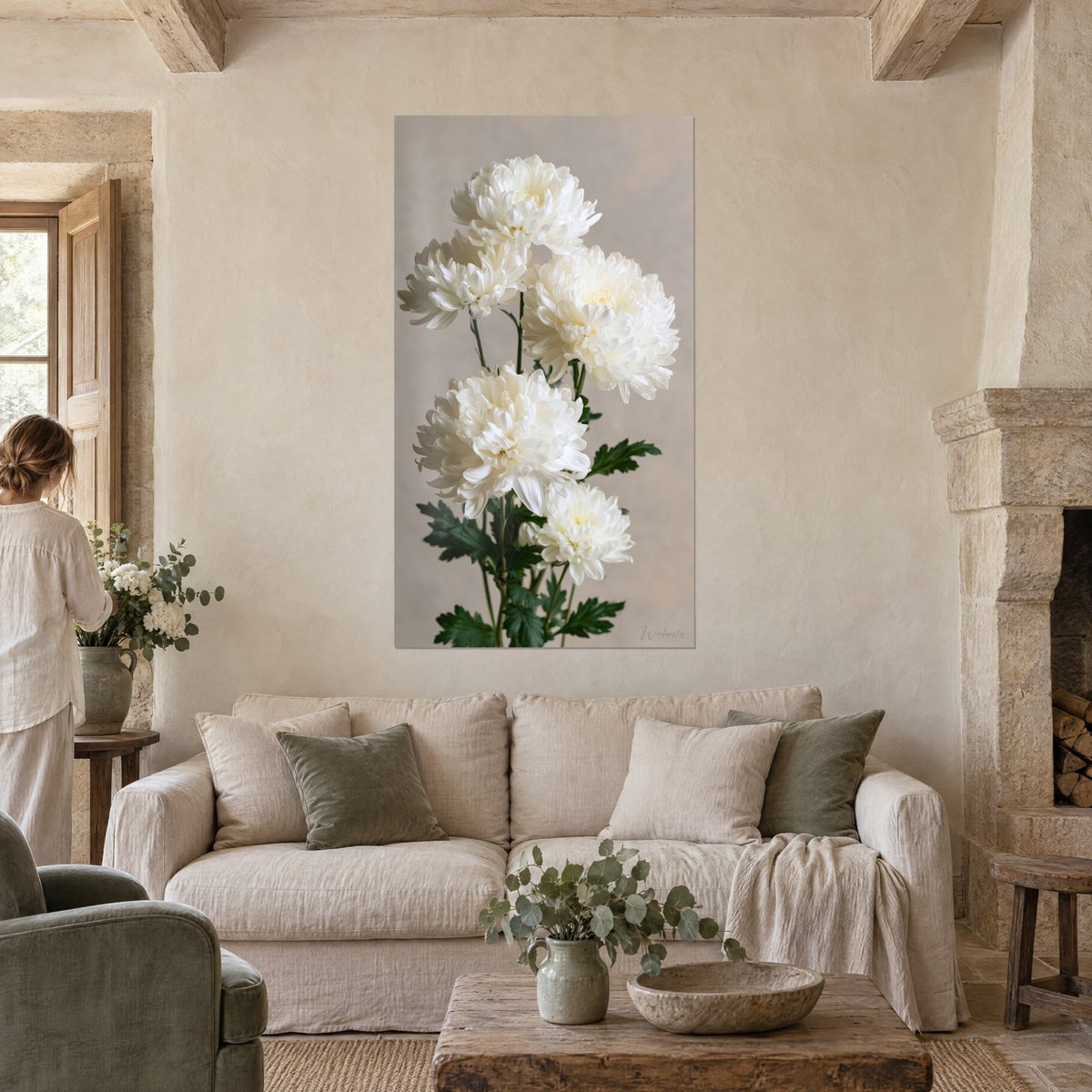 Gemälde Trauben weißer Chrysanthemen mit cremefarbenem Herz und dunkelgrünem Laub, Person von hinten, über einem Sofa in einem hellen Wohnzimmer