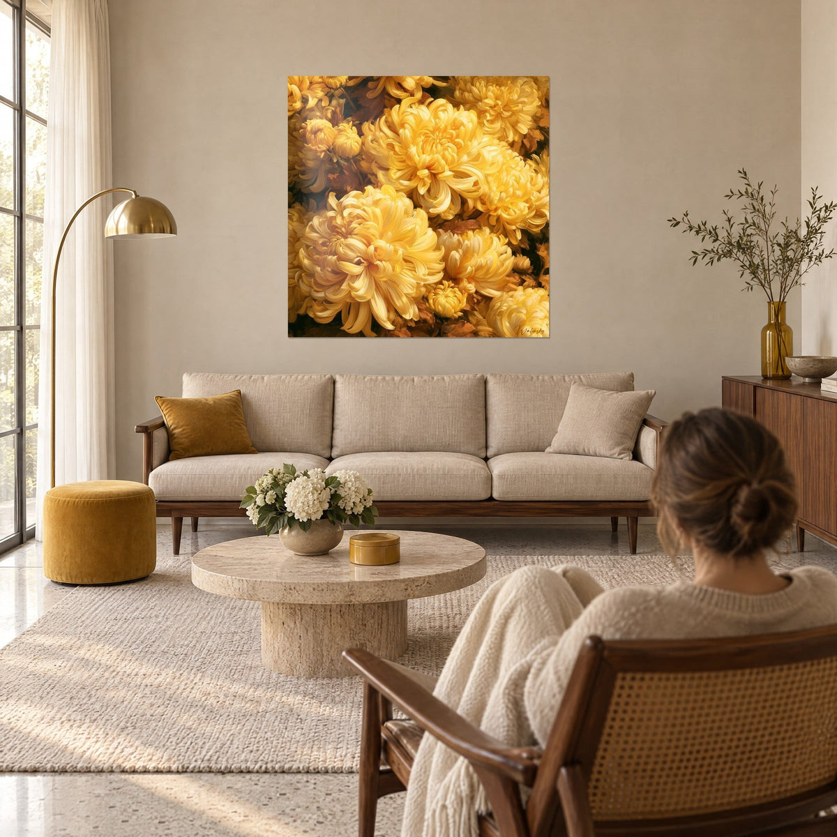 Tableau chrysanthèmes jaune beurre aux pétales frisés, fonds bruns, femme de dos, au-dessus d'un canapé dans un salon lumineux