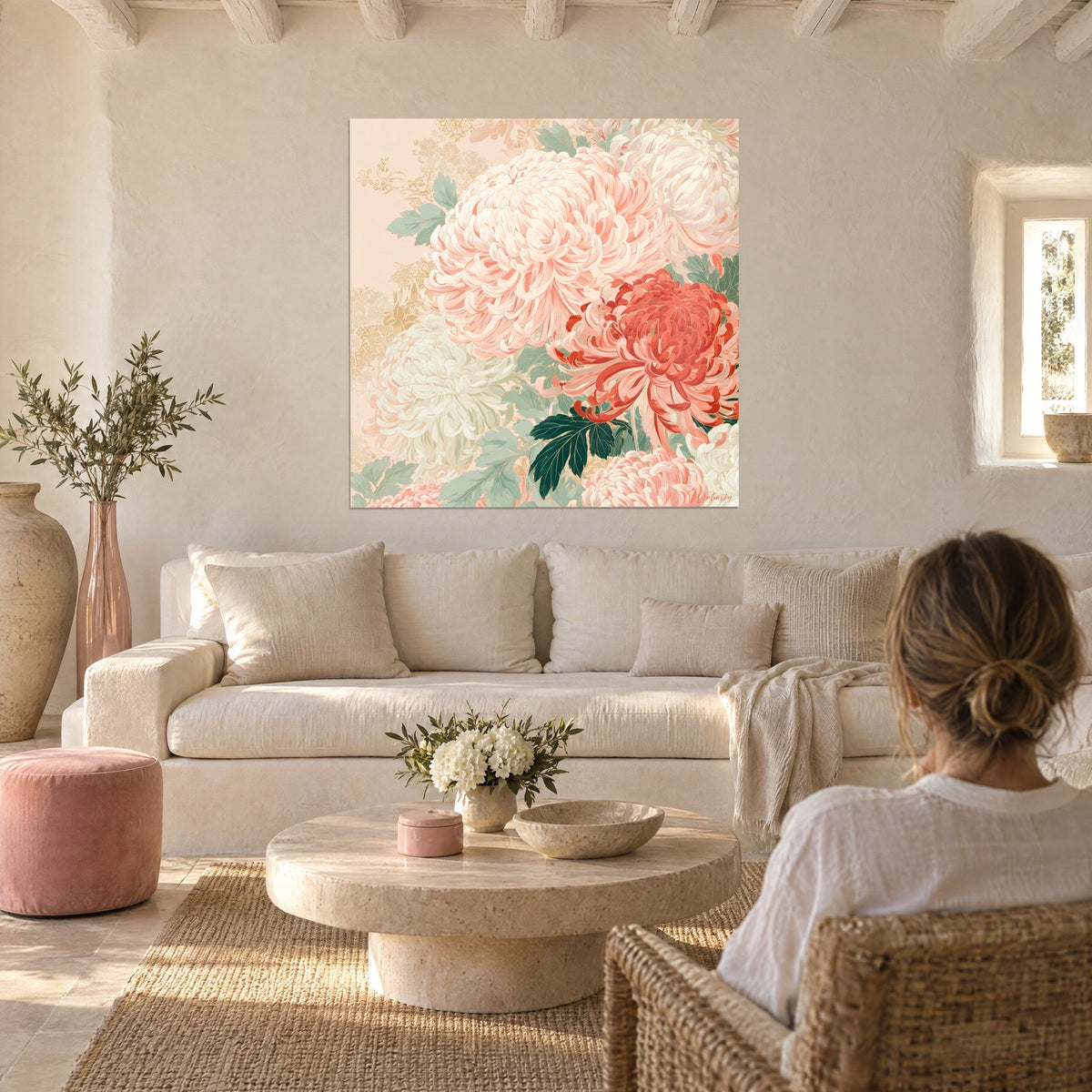 Tableau chrysanthèmes roses épanouis et fleur rouge corail, feuilles vert sauge, au-dessus d'un canapé dans un salon lumineux