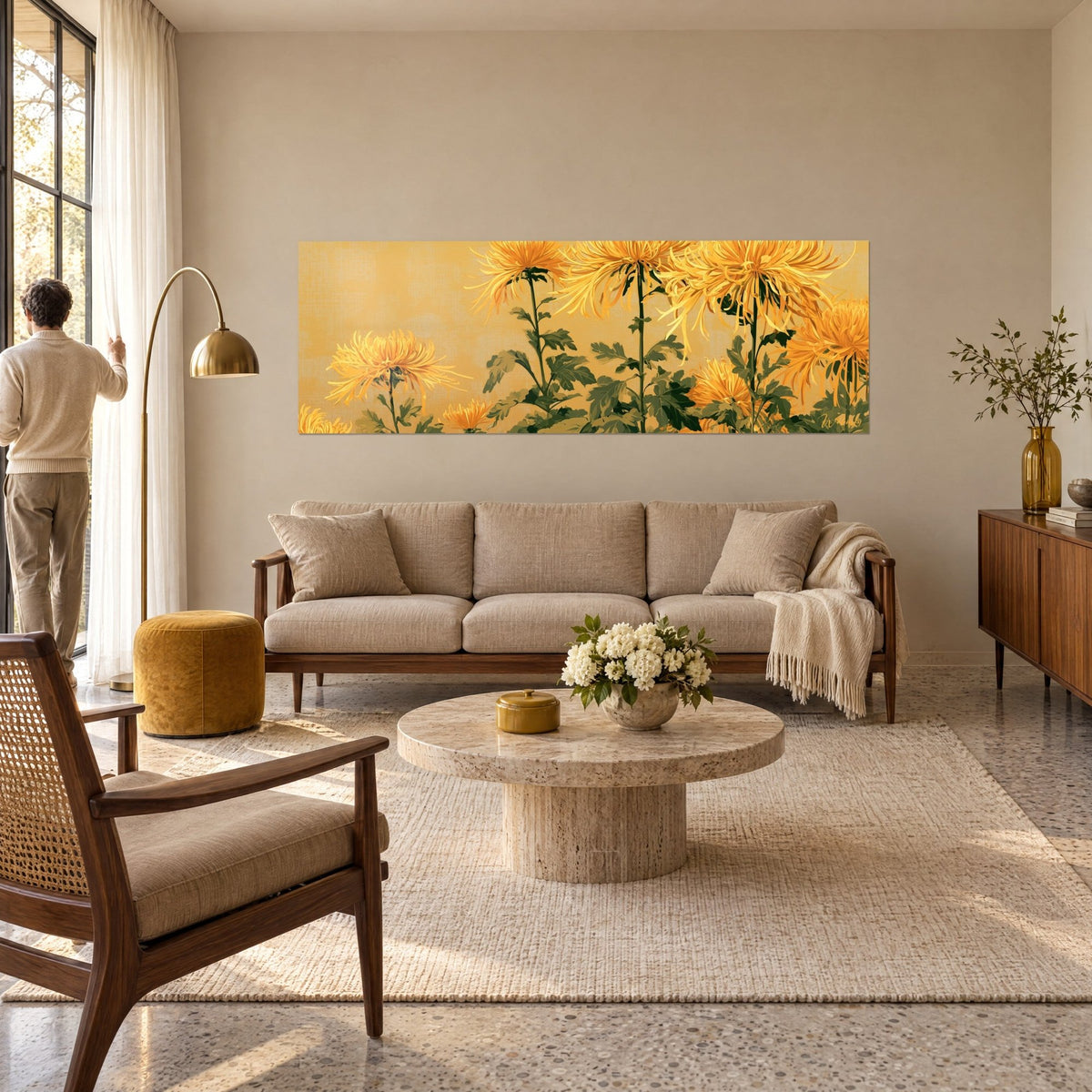 Tableau chrysanthèmes dorés aux pétales filiformes sur fond ocre, tiges vertes élancées, au-dessus d'un canapé dans un salon lumineux