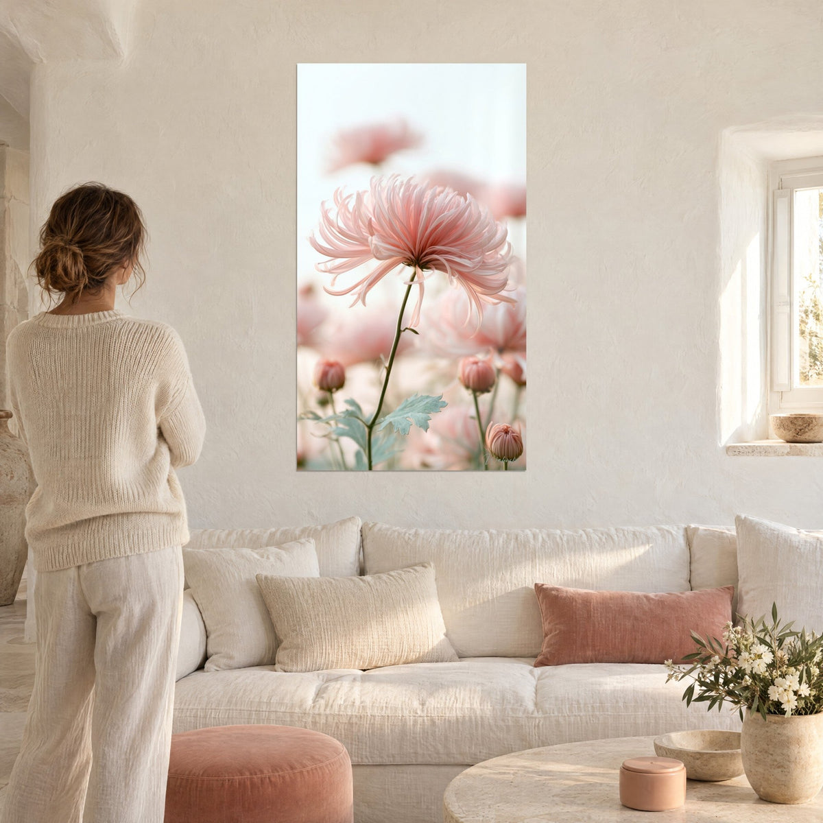 Tableau chrysanthème aux pétales rose poudré effilés, tiges vert sauge, femme de dos, au-dessus d'un canapé dans un salon lumineux