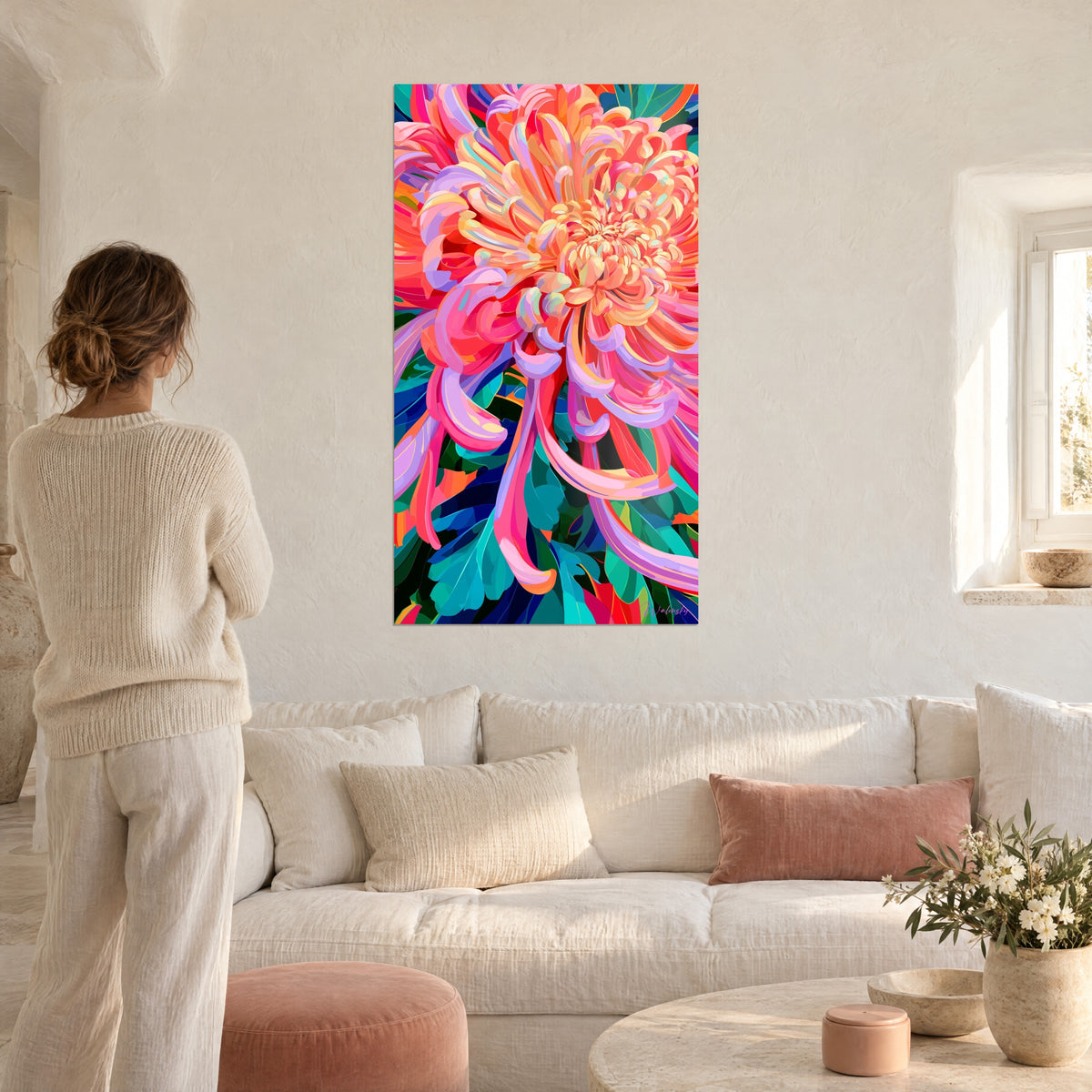 Cuadro crisantemo gigante de pétalos coral y lavanda, follaje turquesa, contemplado por una mujer de espaldas, sobre un sofá en un salón luminoso
