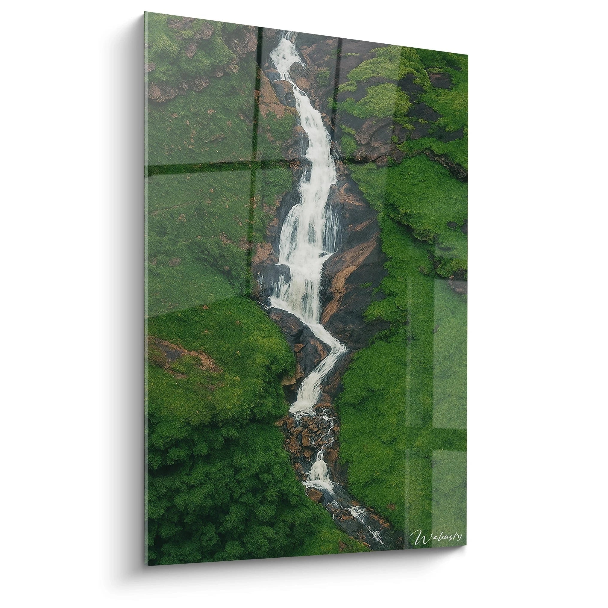 Un tableau artistique représentant une cascade vue aérienne serpentant entre des falaises verdoyantes, avec des eaux blanches contrastant avec la verdure luxuriante et les roches brunes, offrant une perspective plongeante saisissante.
