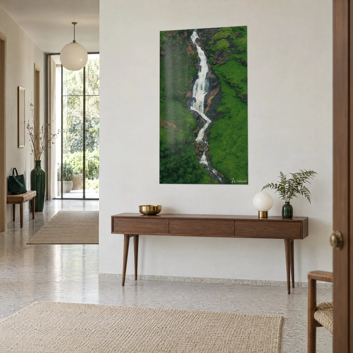 Tableau chute d'eau écumeuse vue du ciel, rochers ocre et prairie émeraude, sur une console en bois dans l'entrée