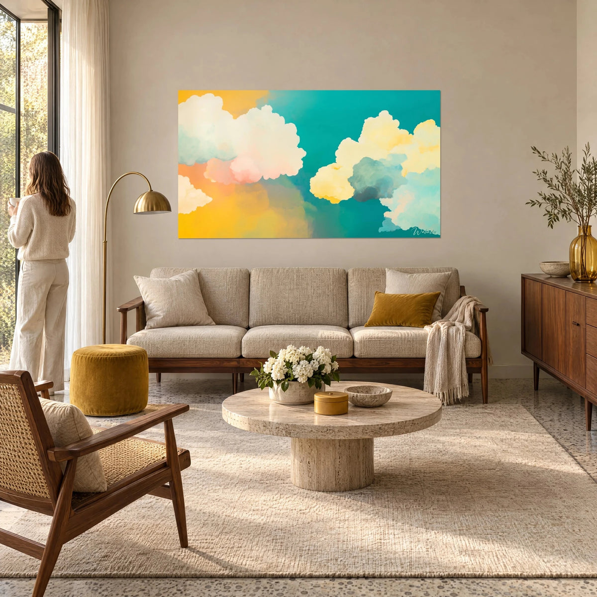 Tableau nuages cotonneux rose pâle et jaune beurre sur ciel turquoise, femme de dos, au-dessus d'un canapé dans un salon lumineux
