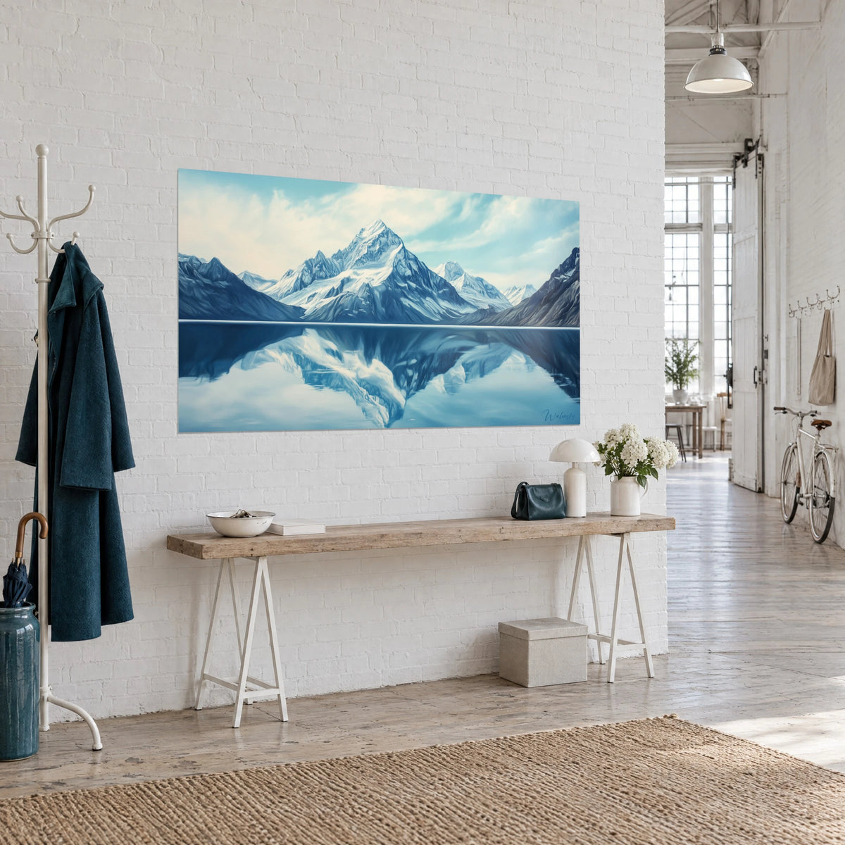 Tableau massif alpin aux arêtes givrées, lac miroir bleu nuit et ciel pâle, accroché sur un mur blanc au loft d'artiste