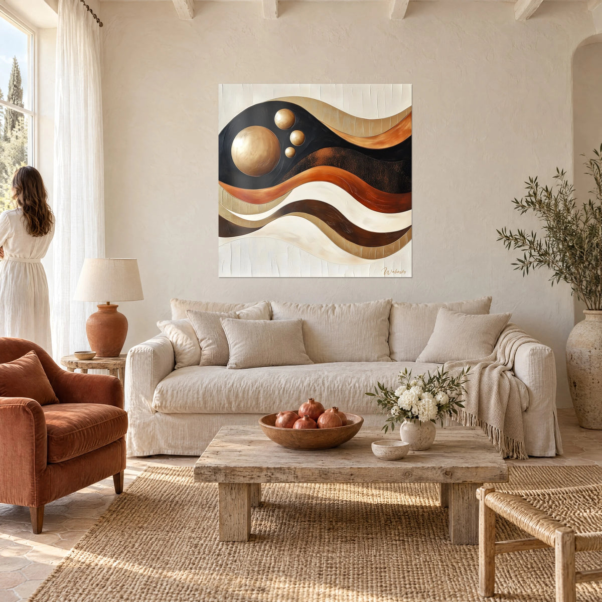 Schilderij met abstracte golven in zwart, oker en koper en gouden bollen, vrouw van achteren, boven een bank in een lichte woonkamer