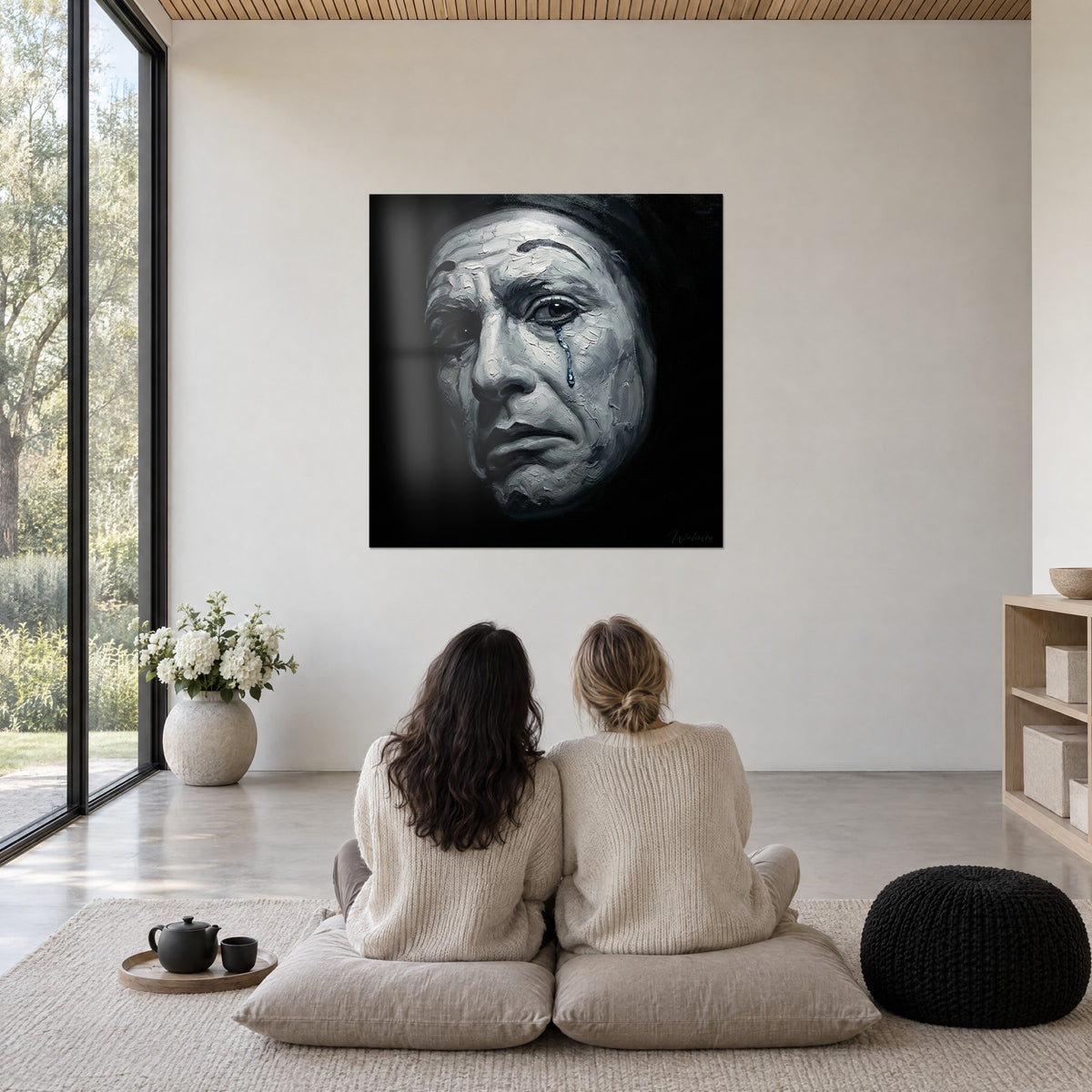 Tableau clown pensif à la larme saphir, visage blanc fendillé et ombres d'encre, devant deux femmes assises sur des coussins