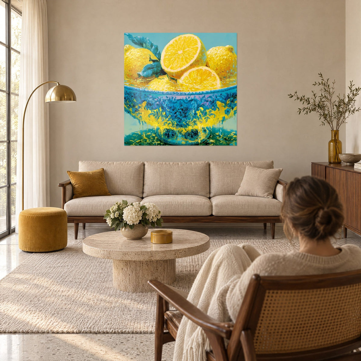 Cuadro cuenco de limones amarillos chorreando pintura, azul turquesa y oro, sobre un sofá en un salón luminoso