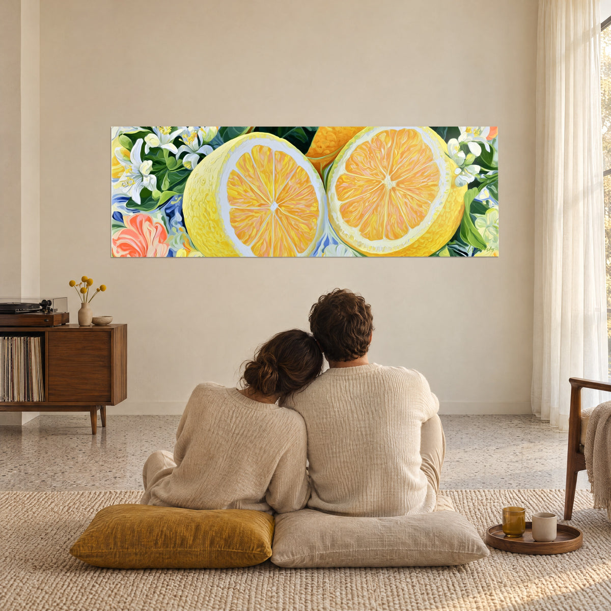 Wall art of blossoming citrus fruits, butter-yellow and apricot-orange slices on a blue and green background, an embracing couple seen from behind on mustard cushions