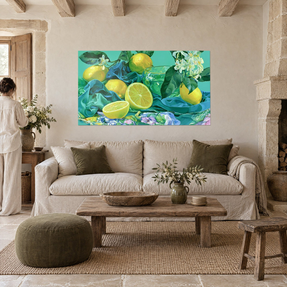 Cuadro limones brillantes sobre seda turquesa, cuenco de cristal y flores blancas, una mujer de espaldas, encima de un sofá en un salón luminoso