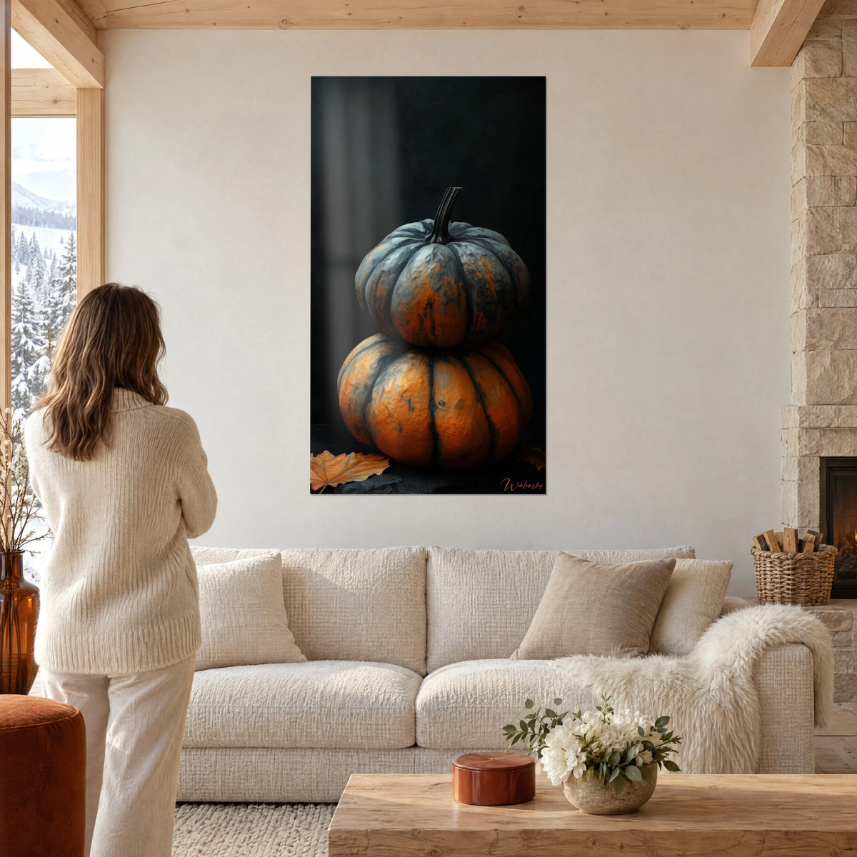 Cuadro dos calabazas apiladas, piel gris azulada y naranja cobrizo sobre fondo negro, encima de un sofá en un salón luminoso