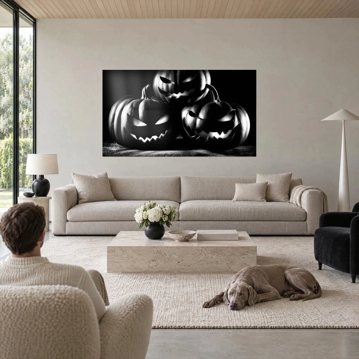Tableau trio de citrouilles grimaçantes en noir et blanc, yeux lumineux, au-dessus d'un canapé dans un salon lumineux