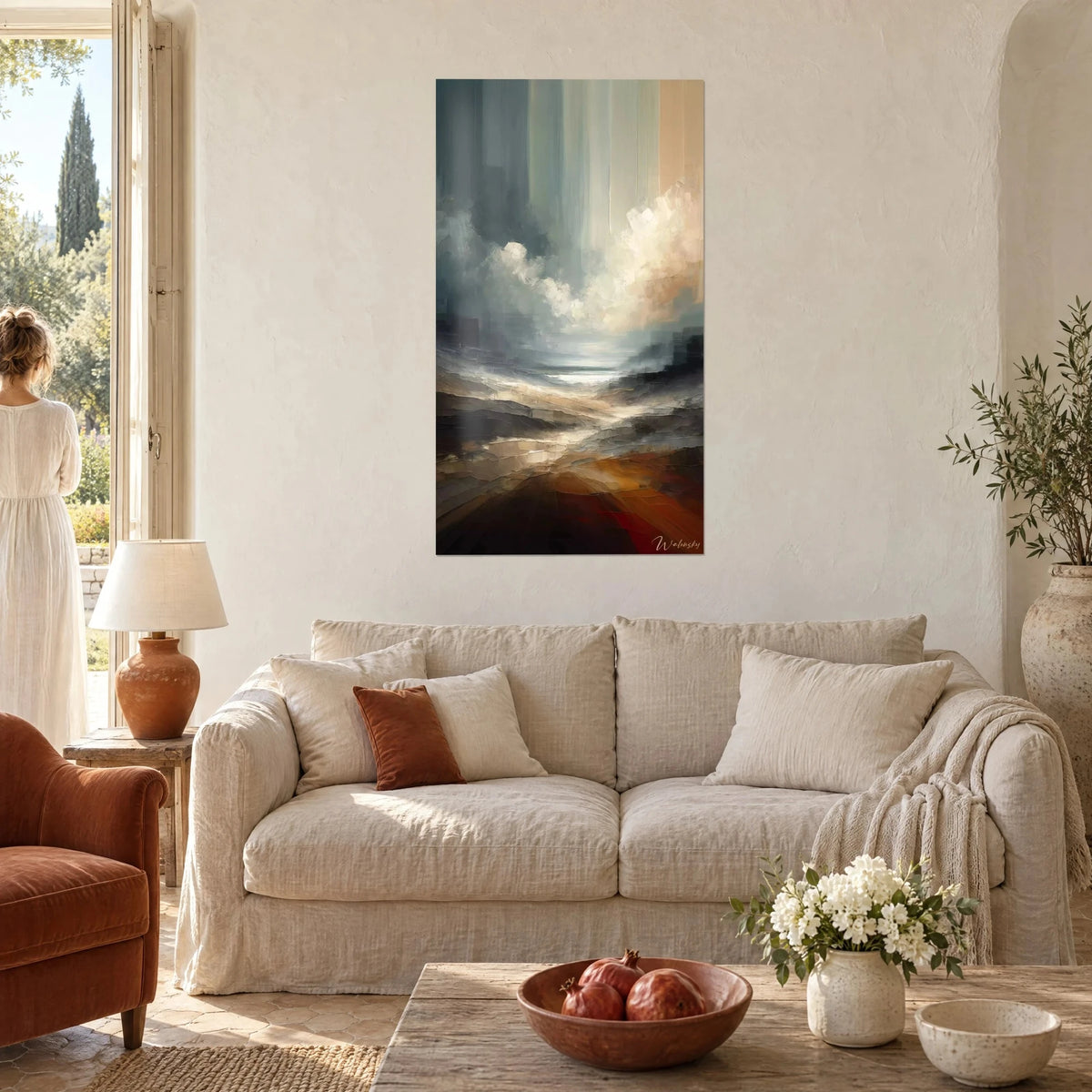Tableau paysage de brume et nuages crème sur fond bleu-gris, sol rouille, une femme de dos, au-dessus d'un canapé dans un salon lumineux