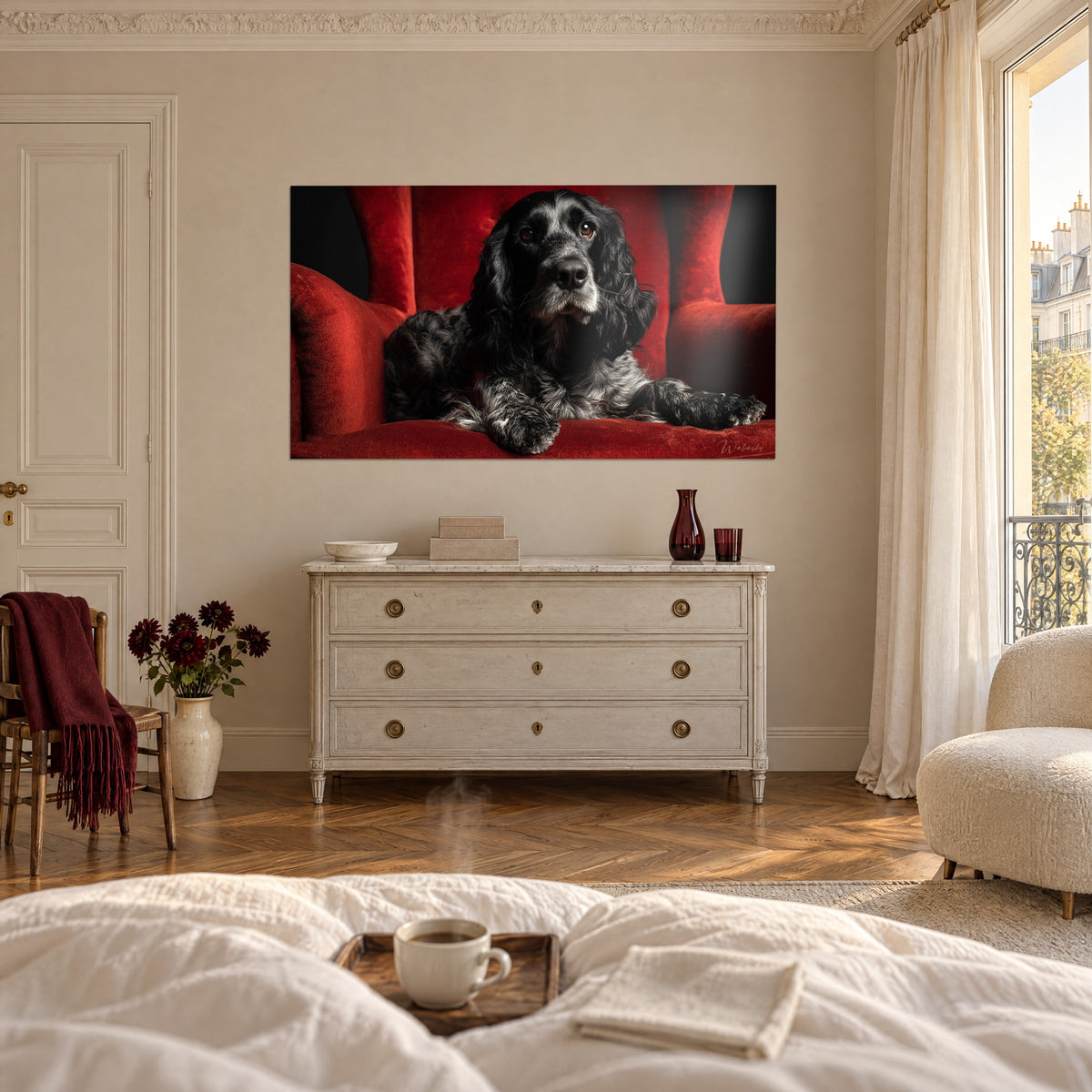 Cuadro de retrato canino negro moteado de gris sobre un sillón rojo, encima de una cama en un dormitorio luminoso
