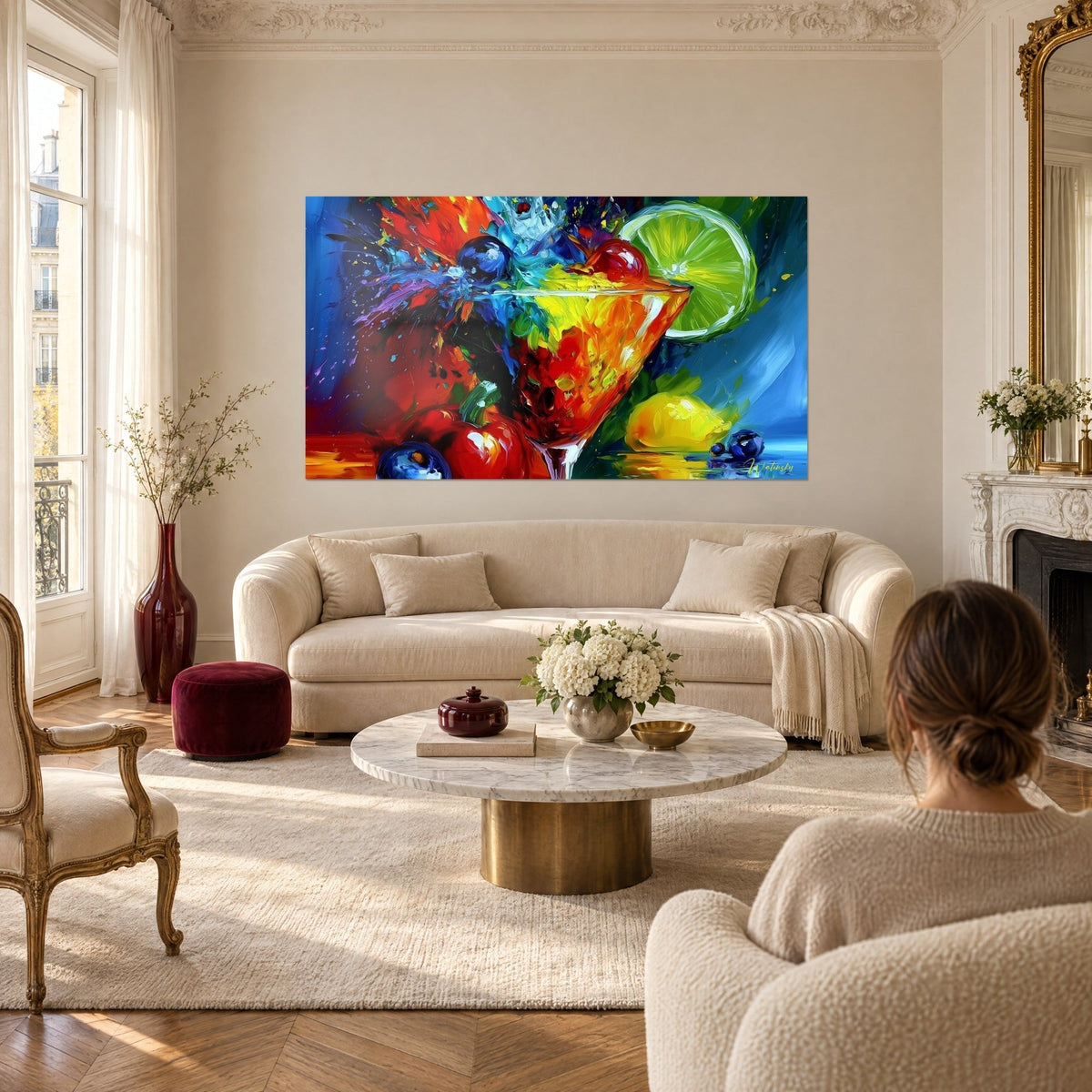 Tableau coupe de cocktail éclaboussée de rouge et d'orange, citron vert à droite, au-dessus d'un canapé dans un salon lumineux