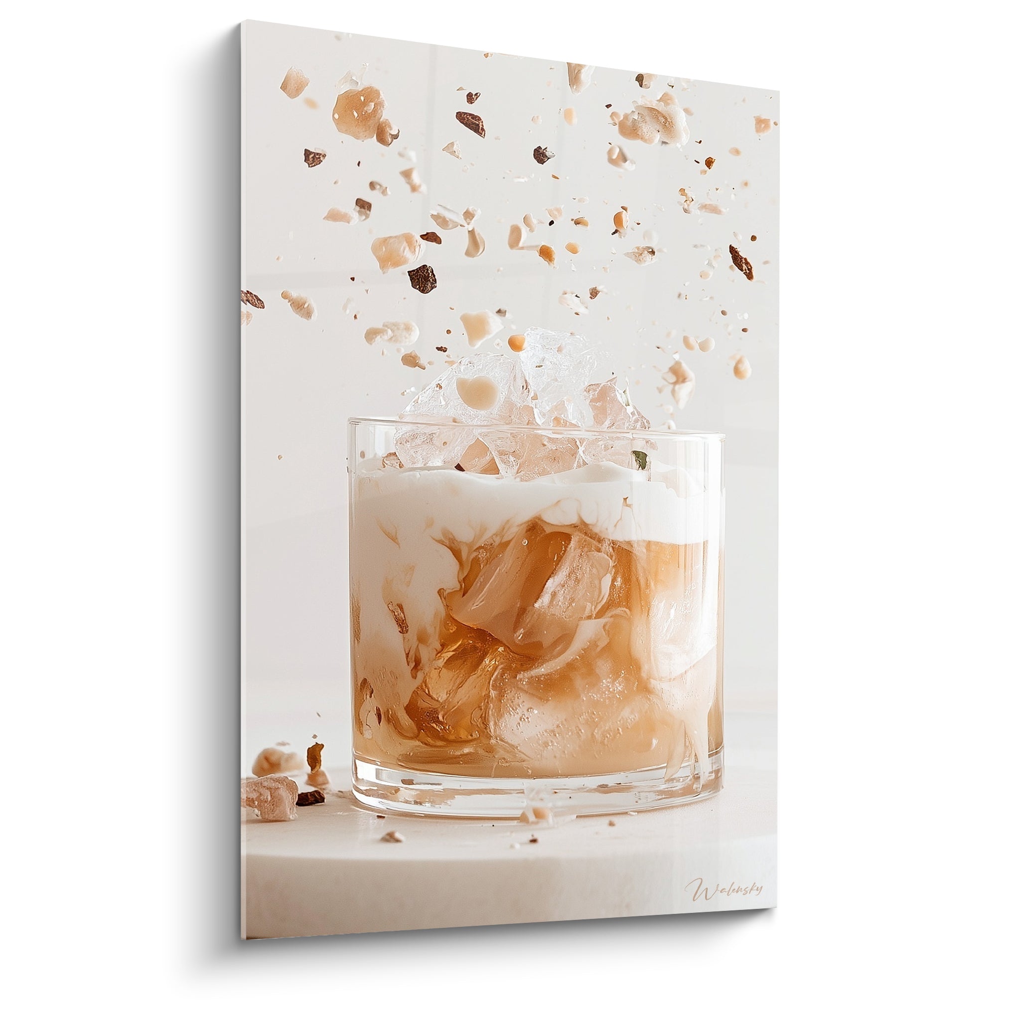 Verre à cocktail caramel et crème avec glaçons et éclats suspendus, fond ivoire lumineux