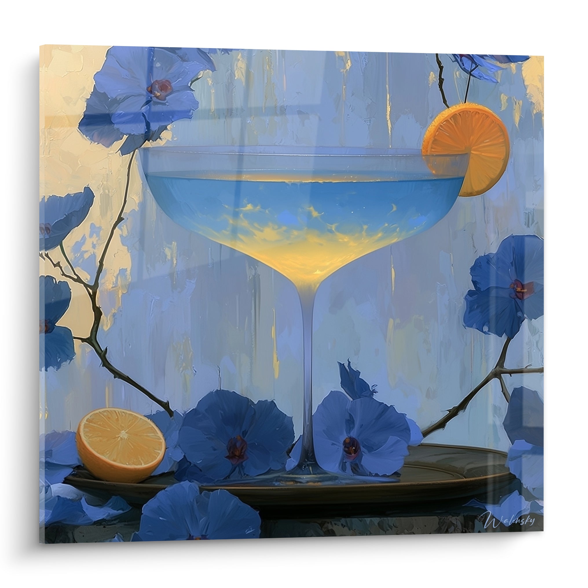 Coupe cocktail bleu pastel et dorée entourée de fleurs bleu marine et d'une tranche d'orange