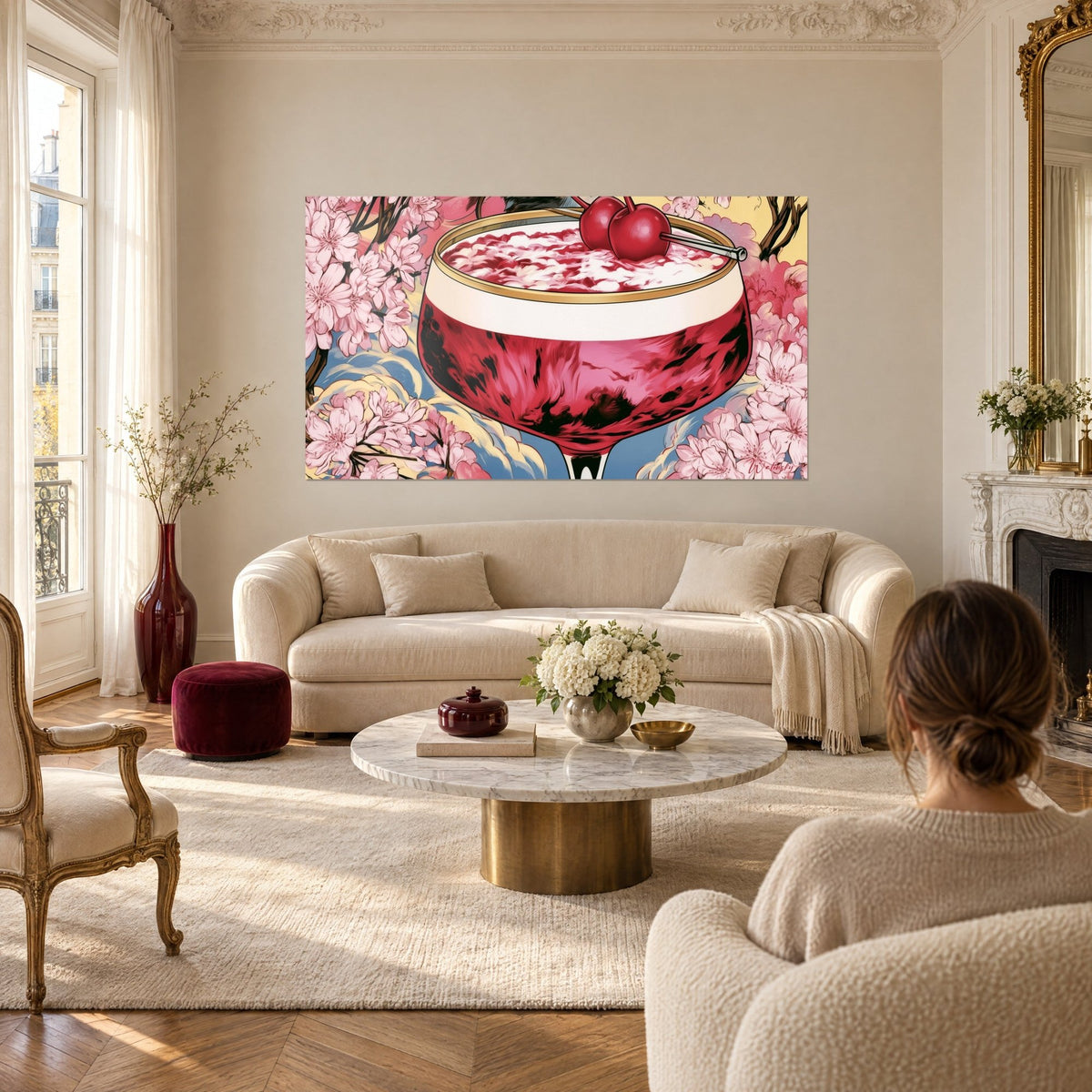Tableau coupe de cocktail rouge cerise bordée d'or, fleurs de cerisier roses, au-dessus d'un canapé dans un salon lumineux
