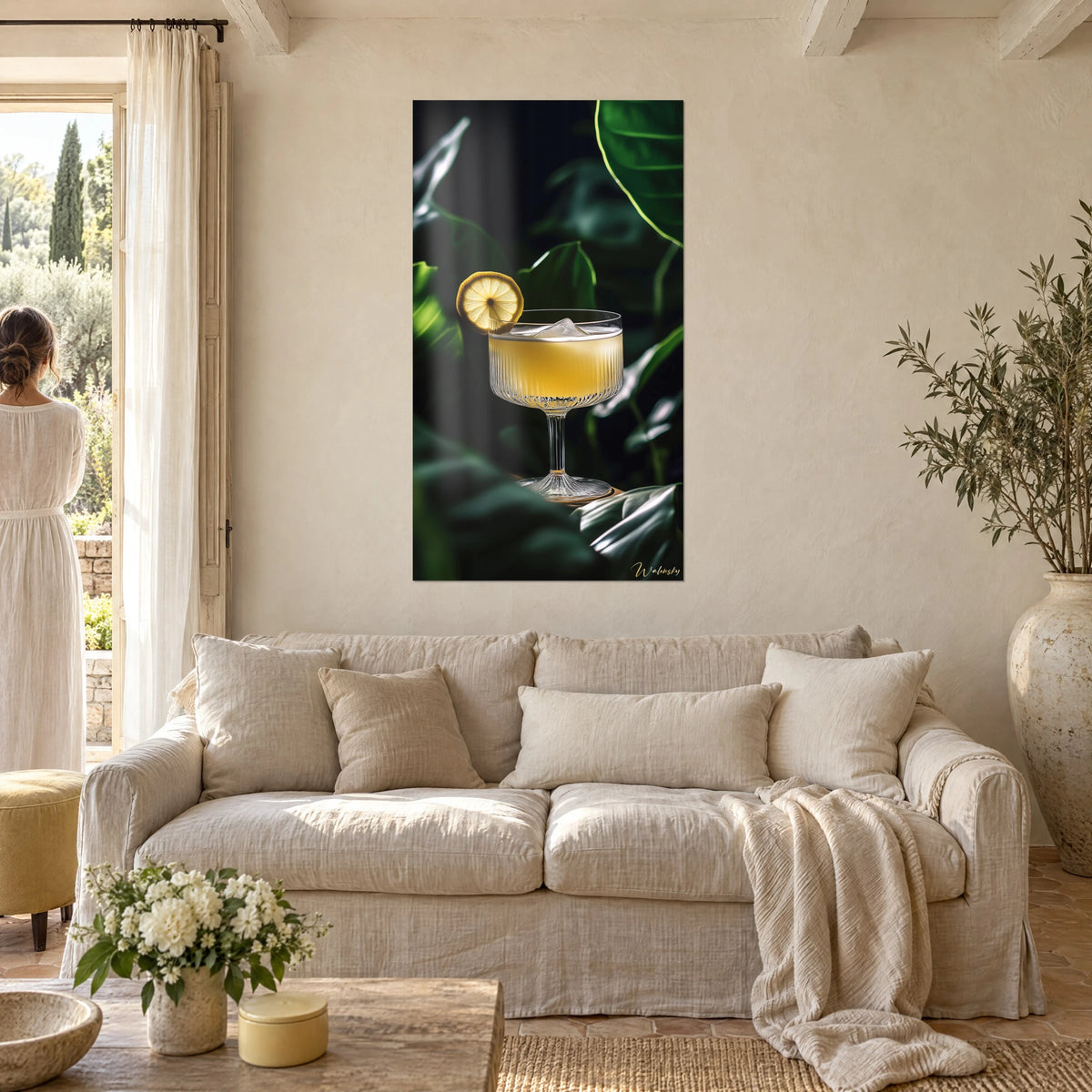 Tableau coupe cannelée de cocktail citronné, tranche de citron dorée, feuillage vert sombre, au-dessus d'un canapé dans un salon lumineux