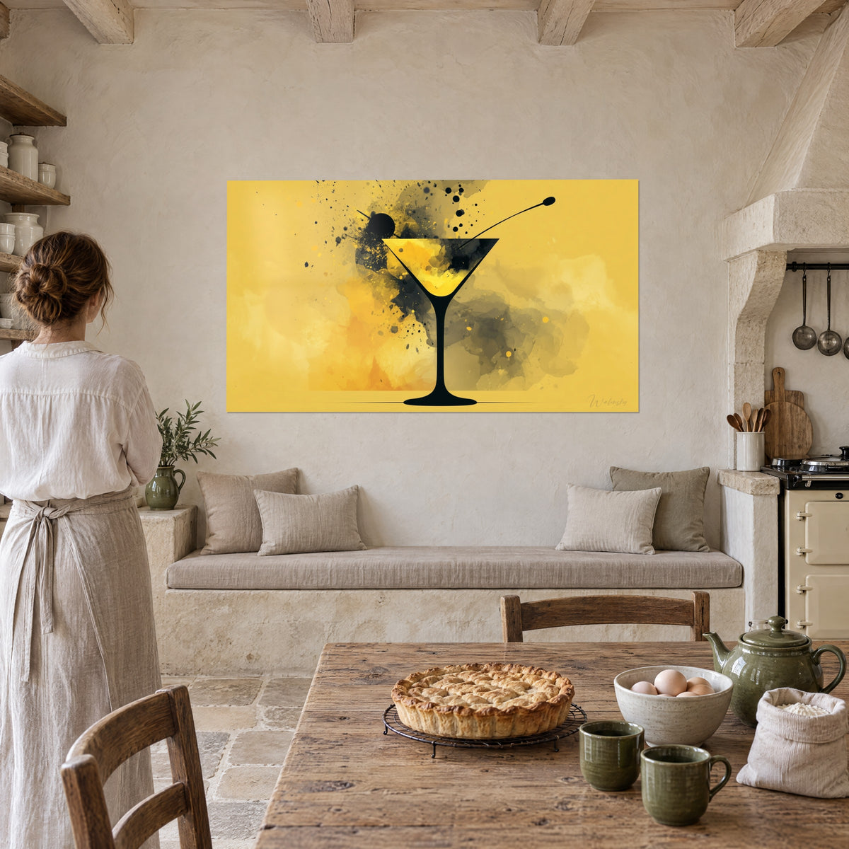 Wall art olive on a pick over a black martini glass, ink drops on yellow and grey watercolour, woman in linen seen from behind in a kitchen