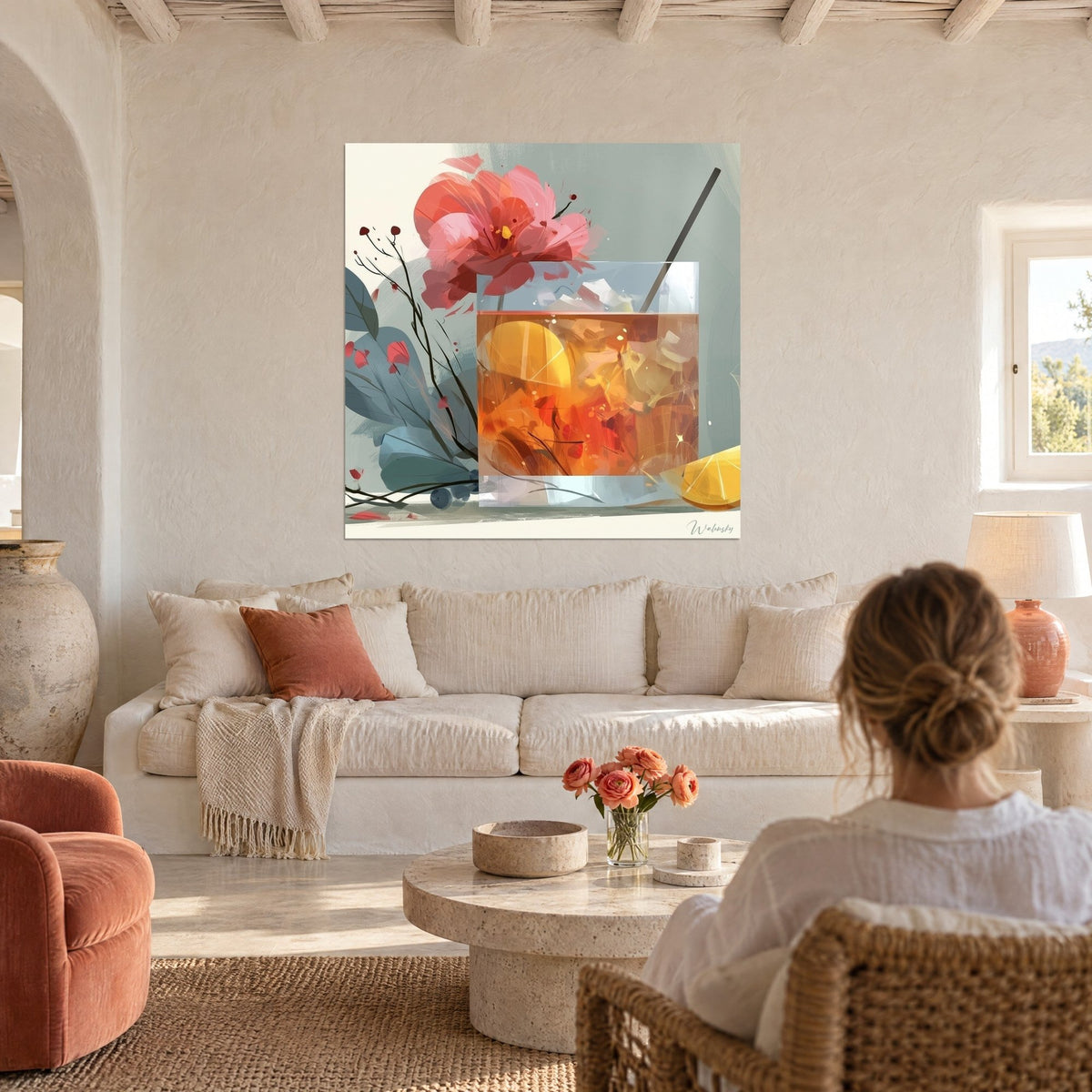 Quadro di un cocktail ambrato con cubetti di ghiaccio, grande fiore rosa corallo, fondo verde rame, donna di spalle, sopra un divano in un soggiorno luminoso