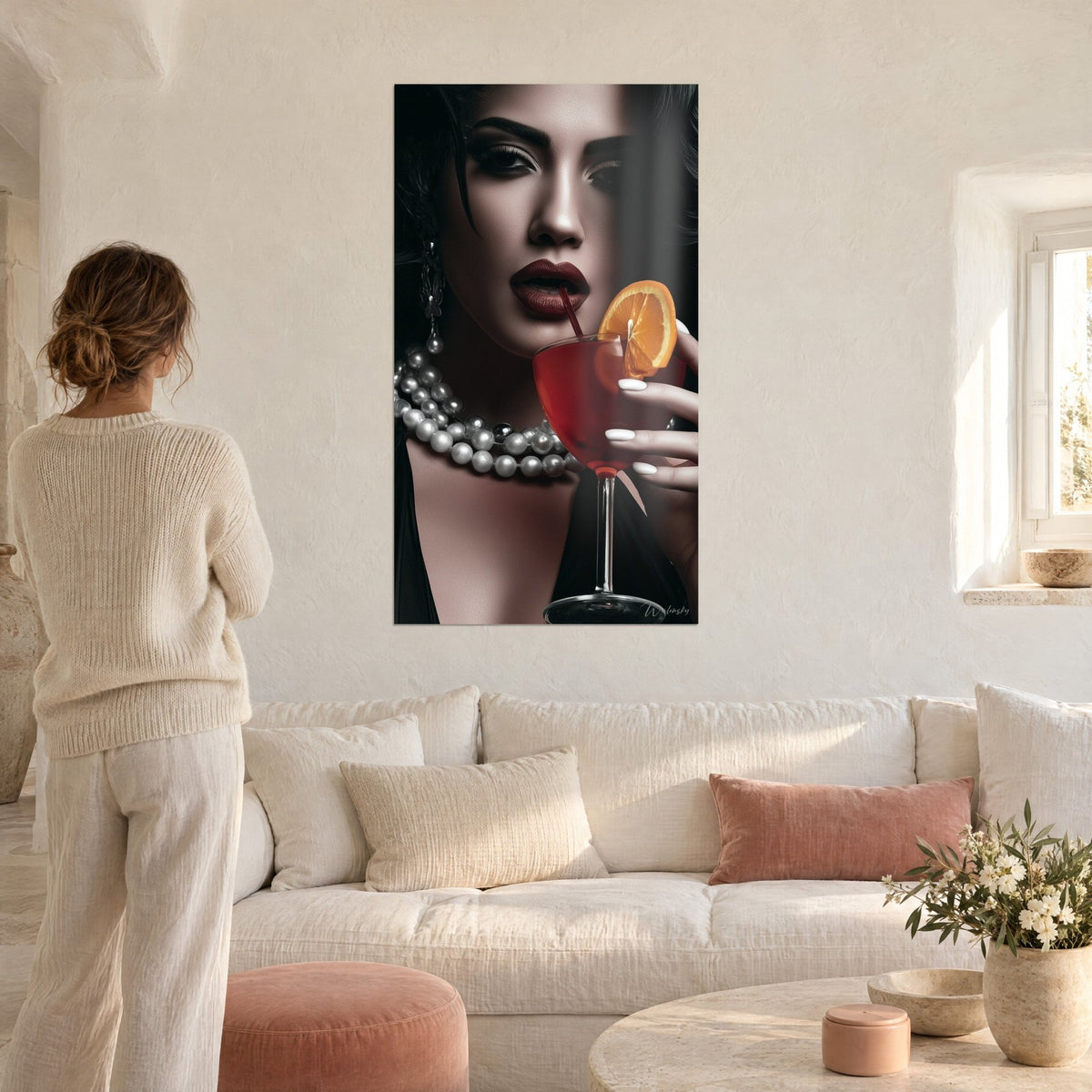 Wall art black and white portrait of a woman with burgundy lips holding a red cocktail, pearl necklaces, hanging above a sofa in a bright living room