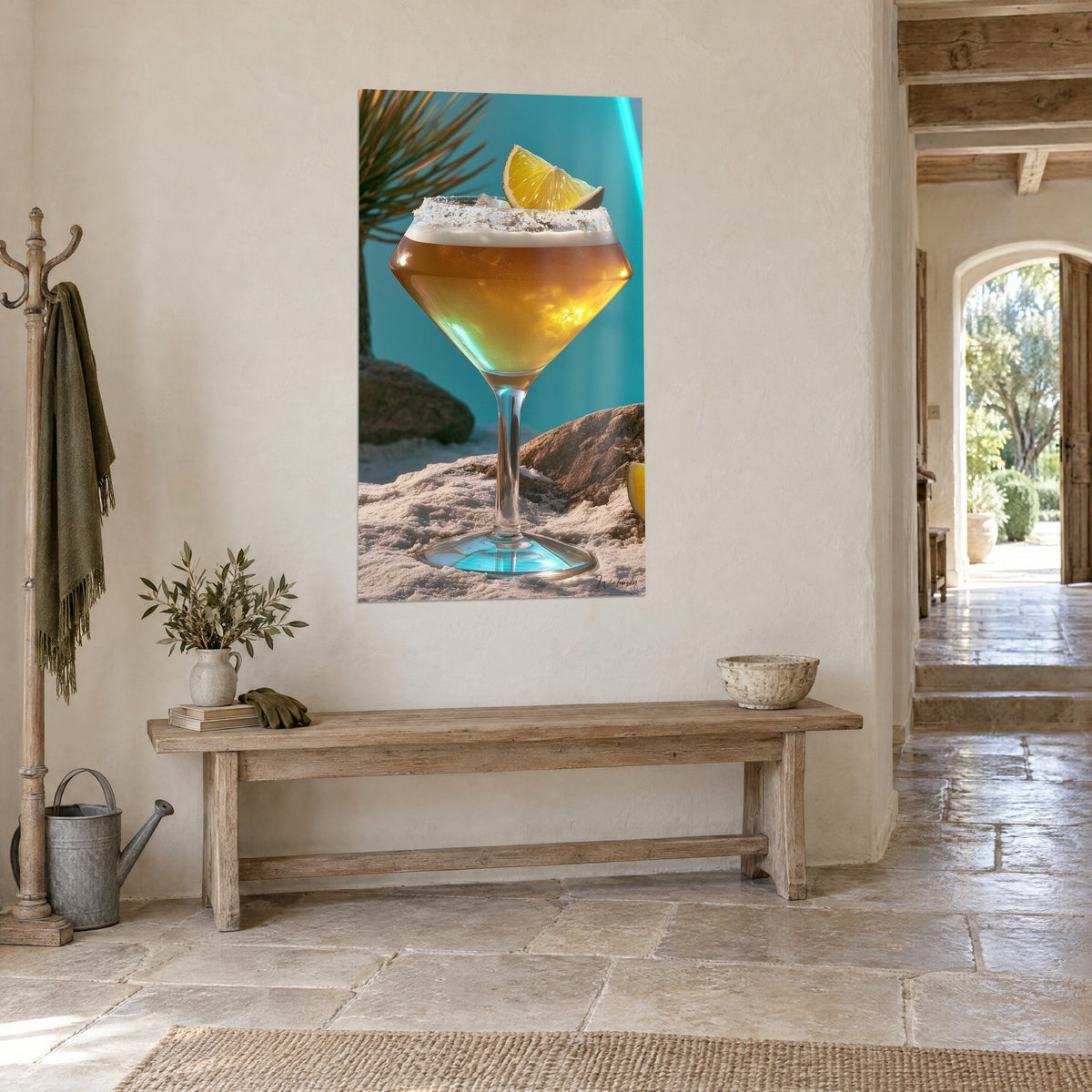 Tableau cocktail doré dans un verre à pied losange, sable blanc et rocher brun, turquoise vif, vu de trois-quarts en maison de pierre