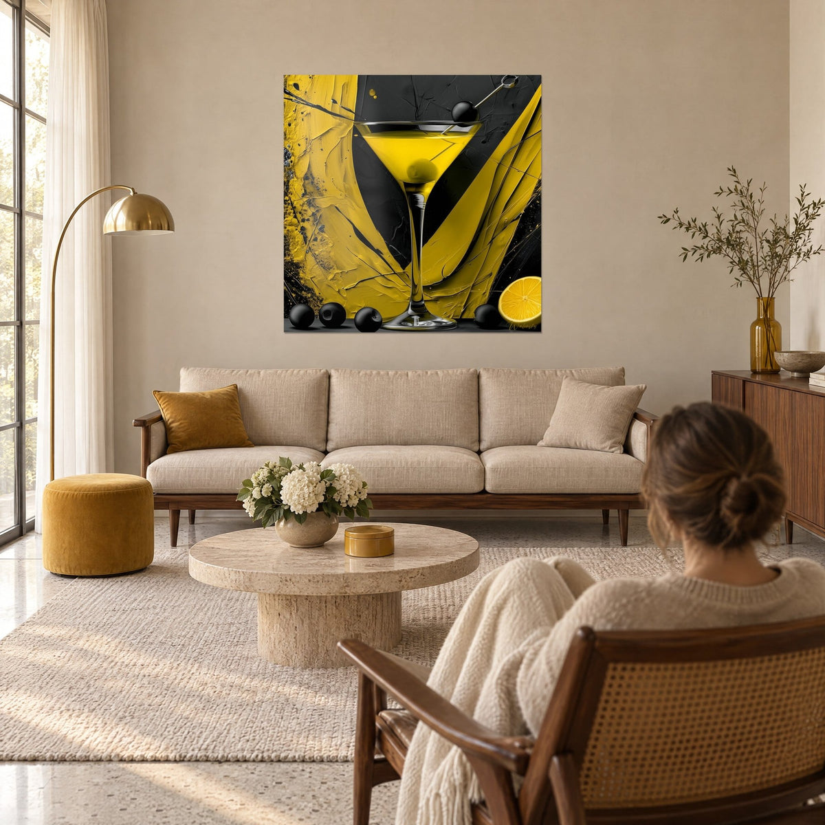 Tableau cocktail martini à l'olive noire, jaune citron et noir, femme de dos, au-dessus d'un canapé dans un salon lumineux