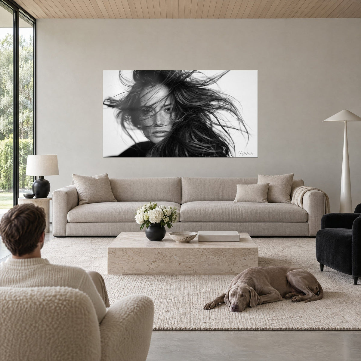Wall art black and white female portrait with wild strands, direct gaze on white background, above a sofa in a bright living room