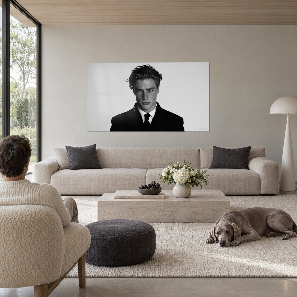 Wall art black and white portrait of a young man with a stern gaze, black suit, light grey background, above a sofa in a bright living room