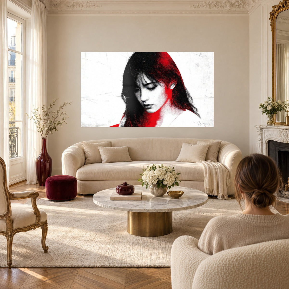 Tableau visage de femme aux cheveux noirs, mèche rouge vif, paupières baissées sur fond blanc, au-dessus d'un canapé dans un salon lumineux