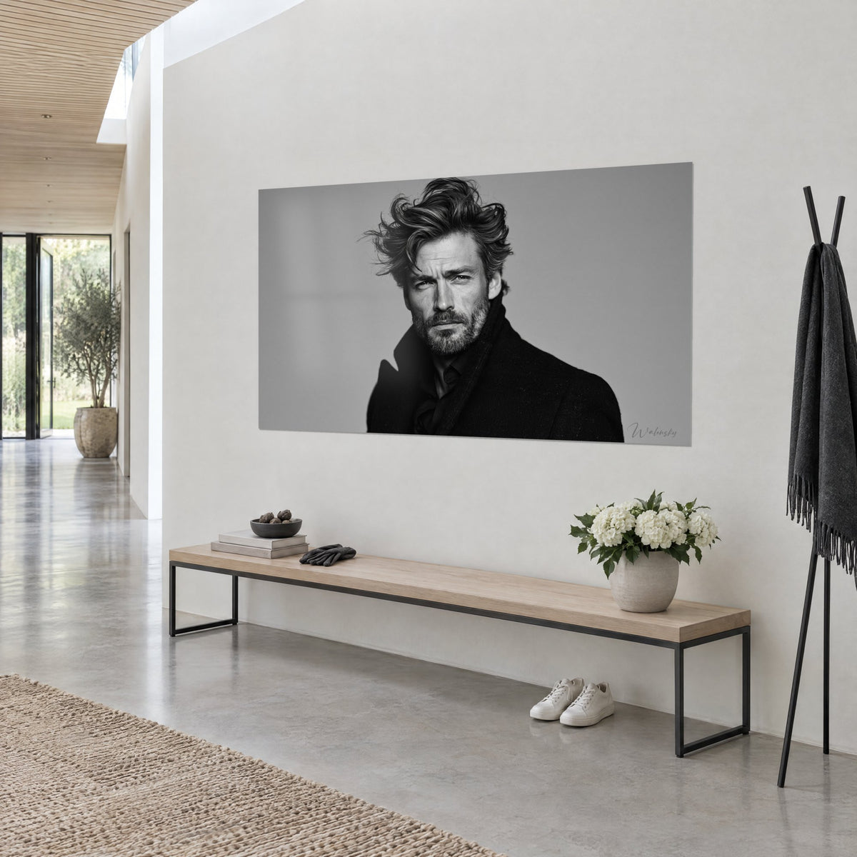 Wall art male face with a serious gaze, salt-and-pepper beard and windswept hair, in black and white, hanging on a white wall